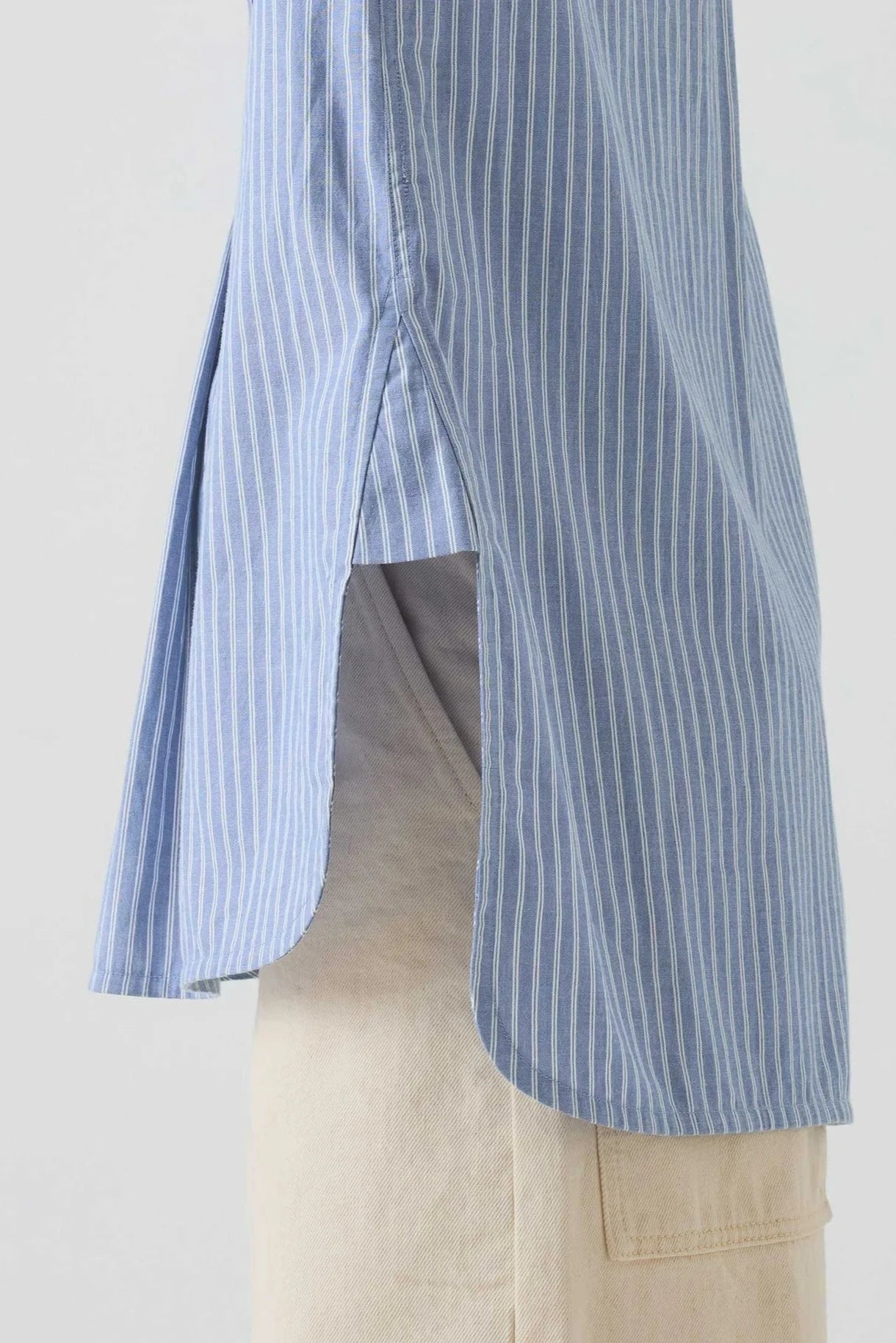Blue and white striped shirt over beige pants on a plain background