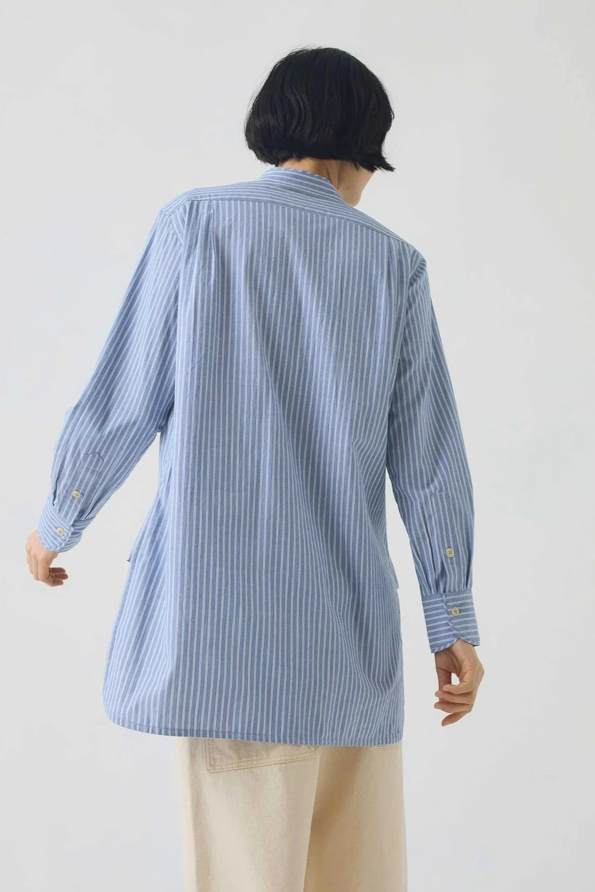 Person wearing a blue striped shirt against a white background, viewed from the back