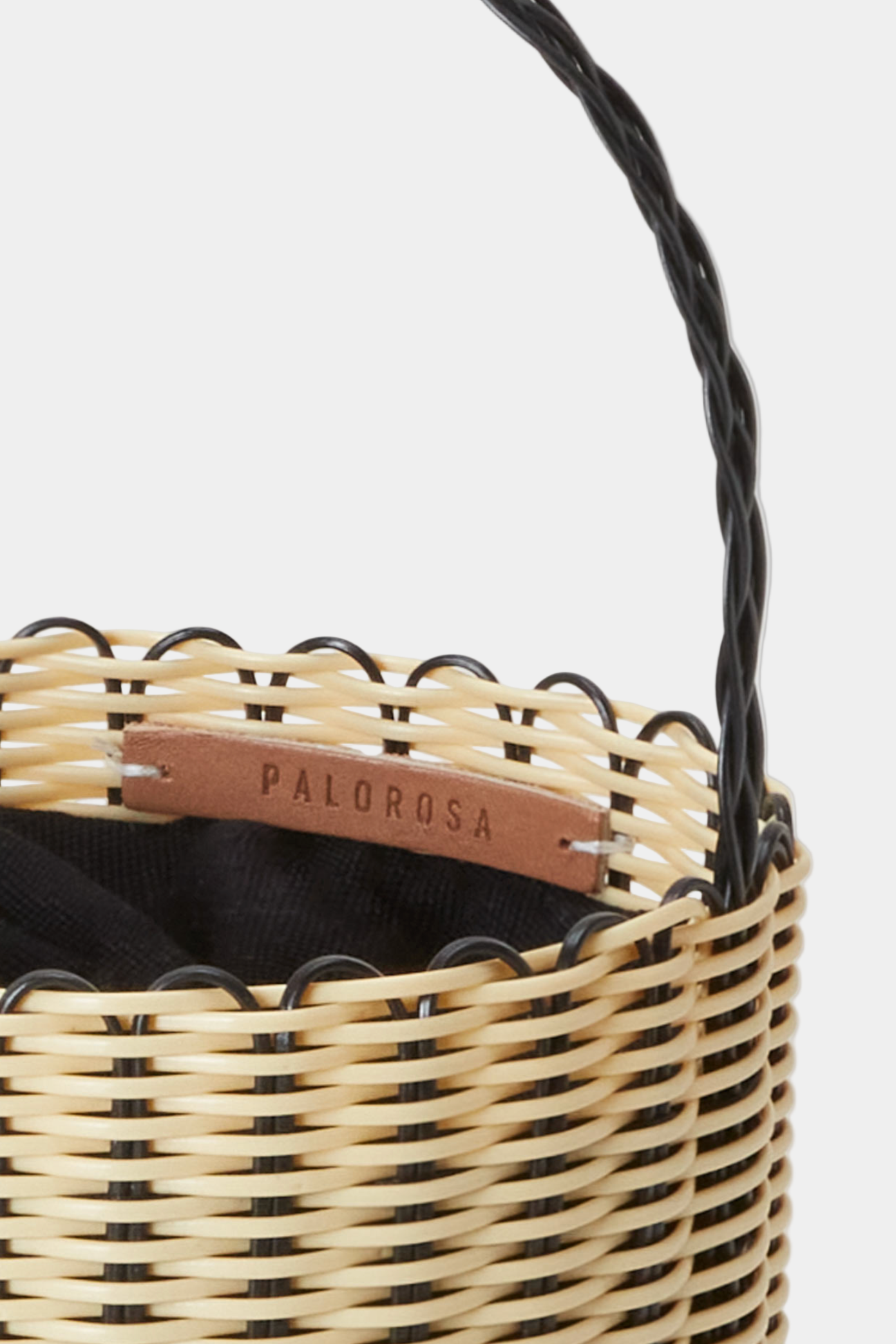 Woven basket with a handle and visible brand name on a light gray background