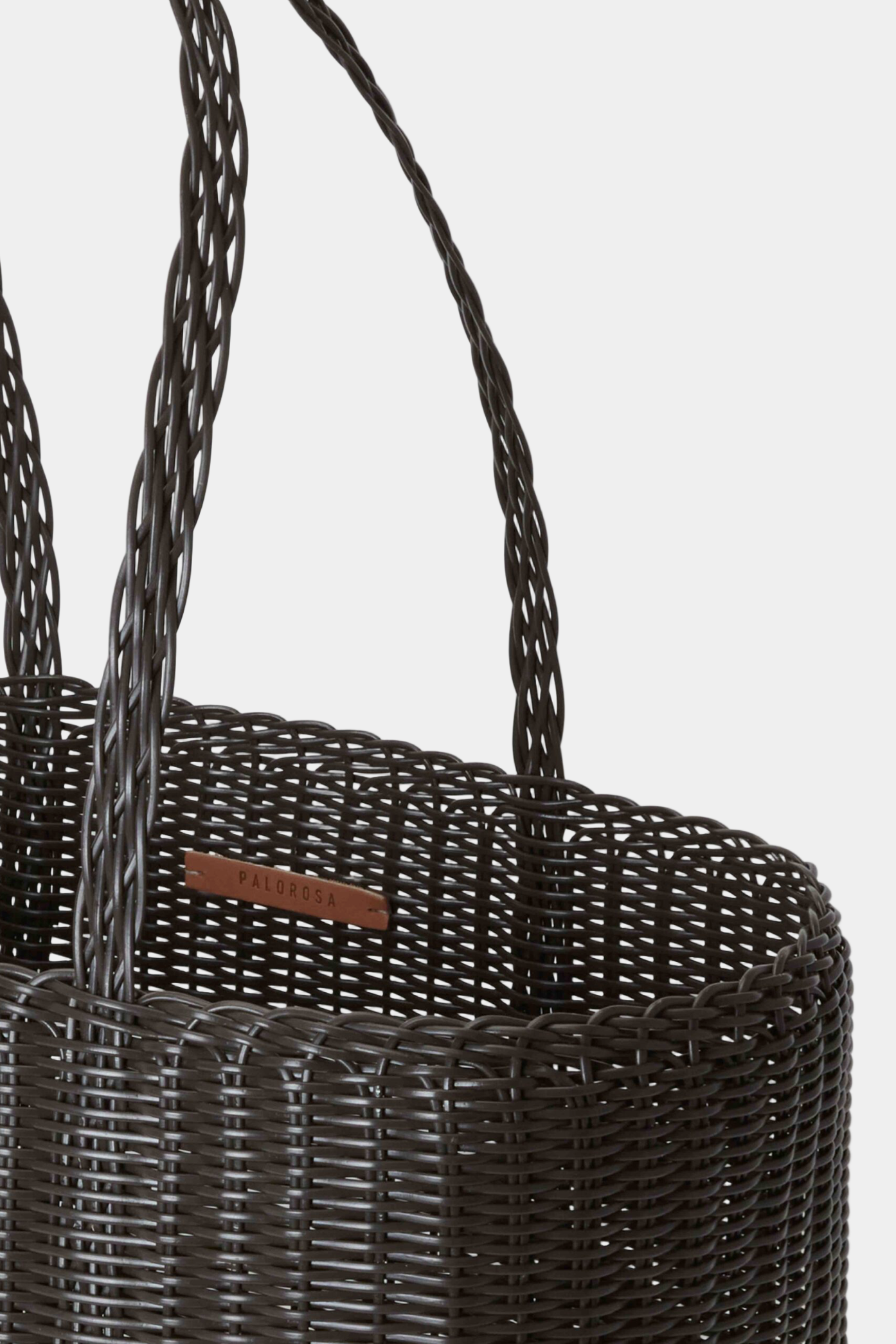 Dark woven basket with a visible brand label on a light gray background