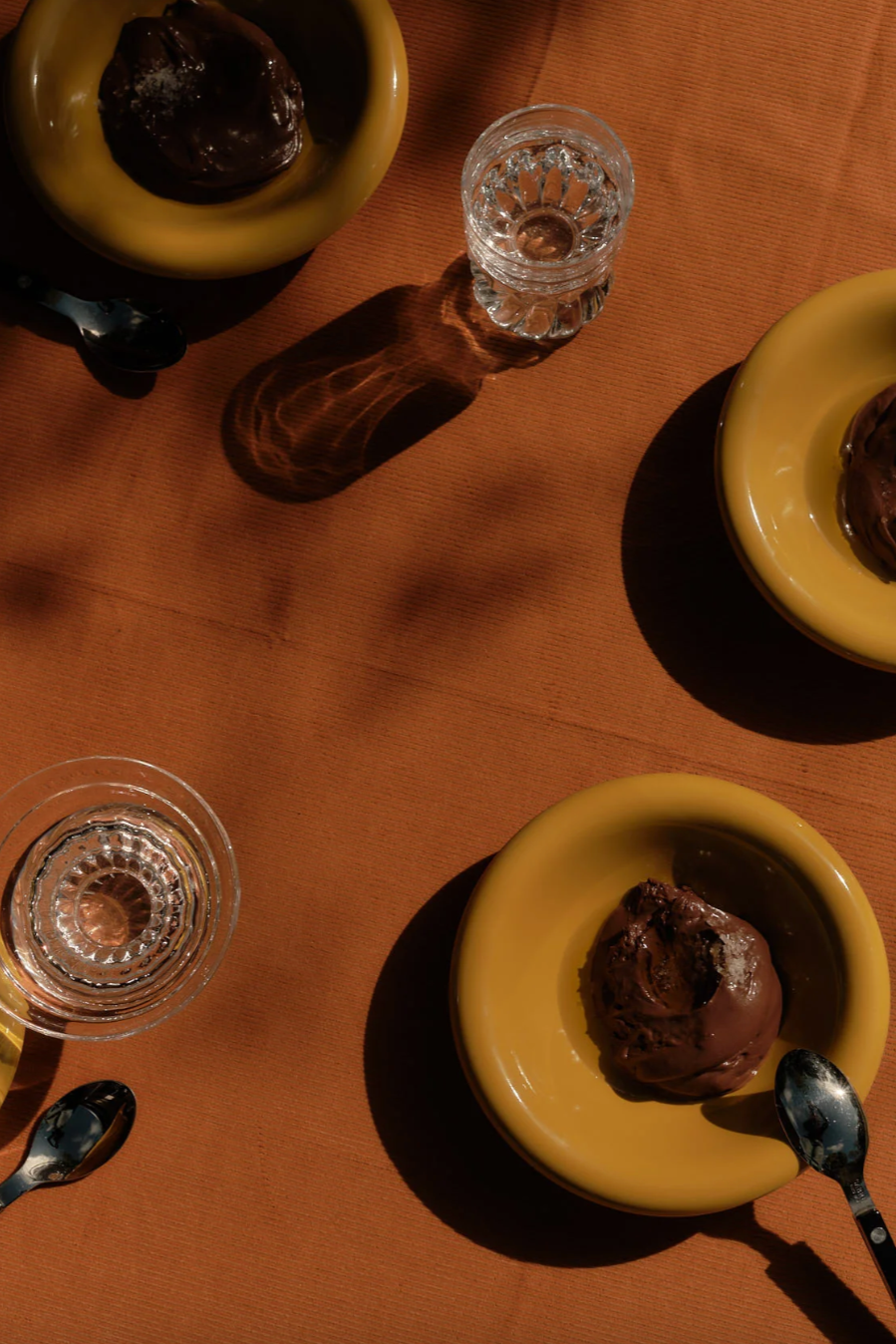 Chocolate dessert in softedge side bowls with spoons on a brown tablecloth