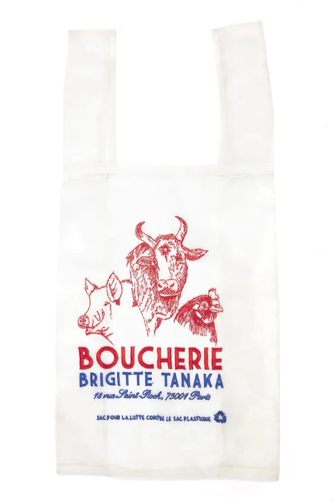 Butcher paper with red and blue text in side a organza embroidered bag with a cow illustration on a white background