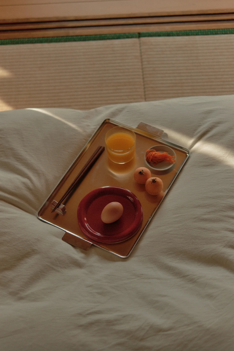 Tray with eggs, a glass of orange juice, and a knife on a white surface