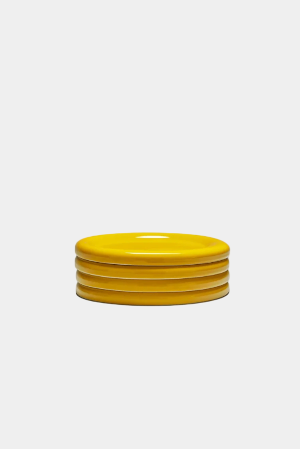 Stack of mustard yellow snack plates on a white background