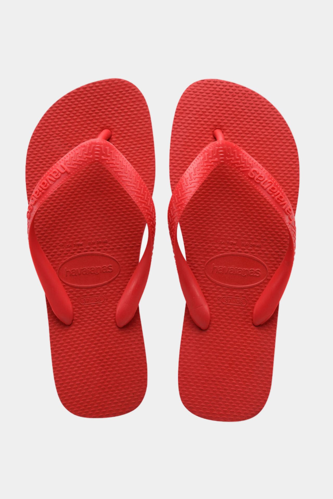 Red flip-flops with a visible brand logo on a light gray background