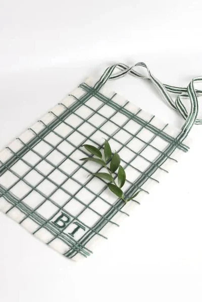 Small green wire grid with a handle on a white background