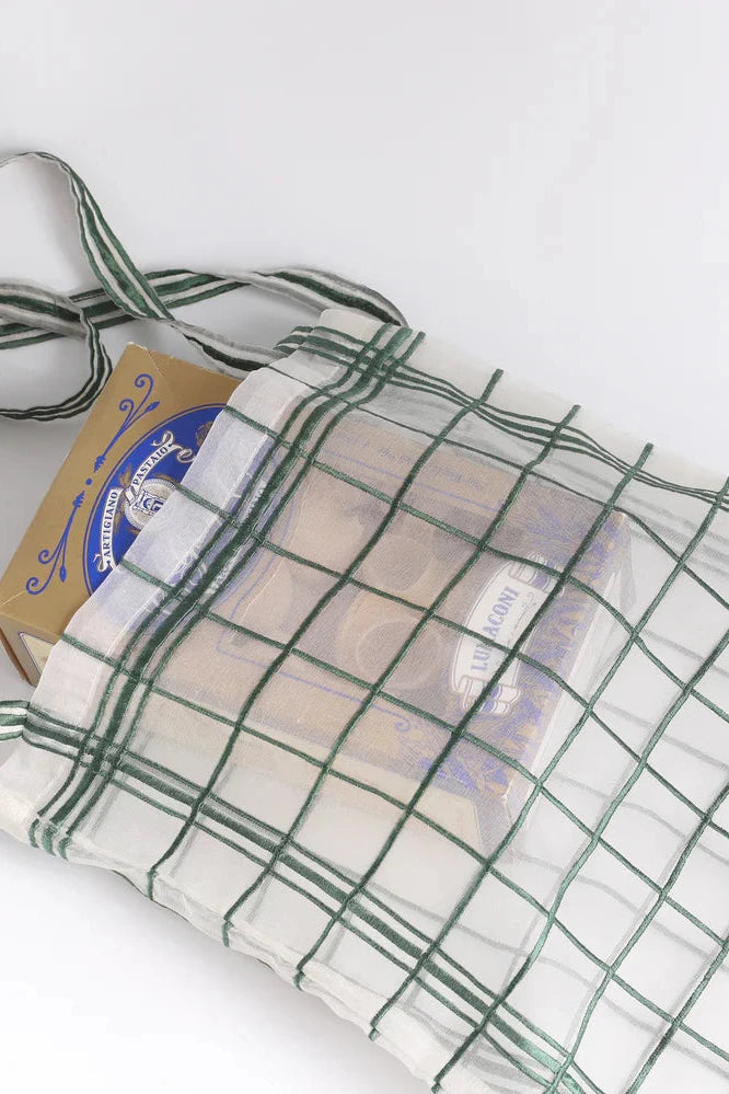 Small green wire grid with a handle on a white background