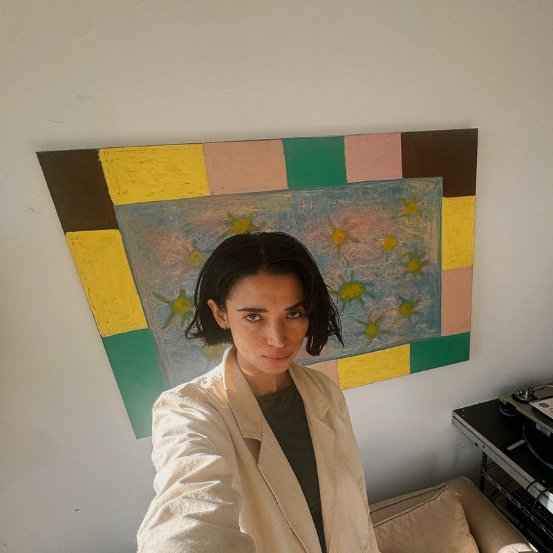 Carla Uriarte standing in front of a painting wearing a cream blazer