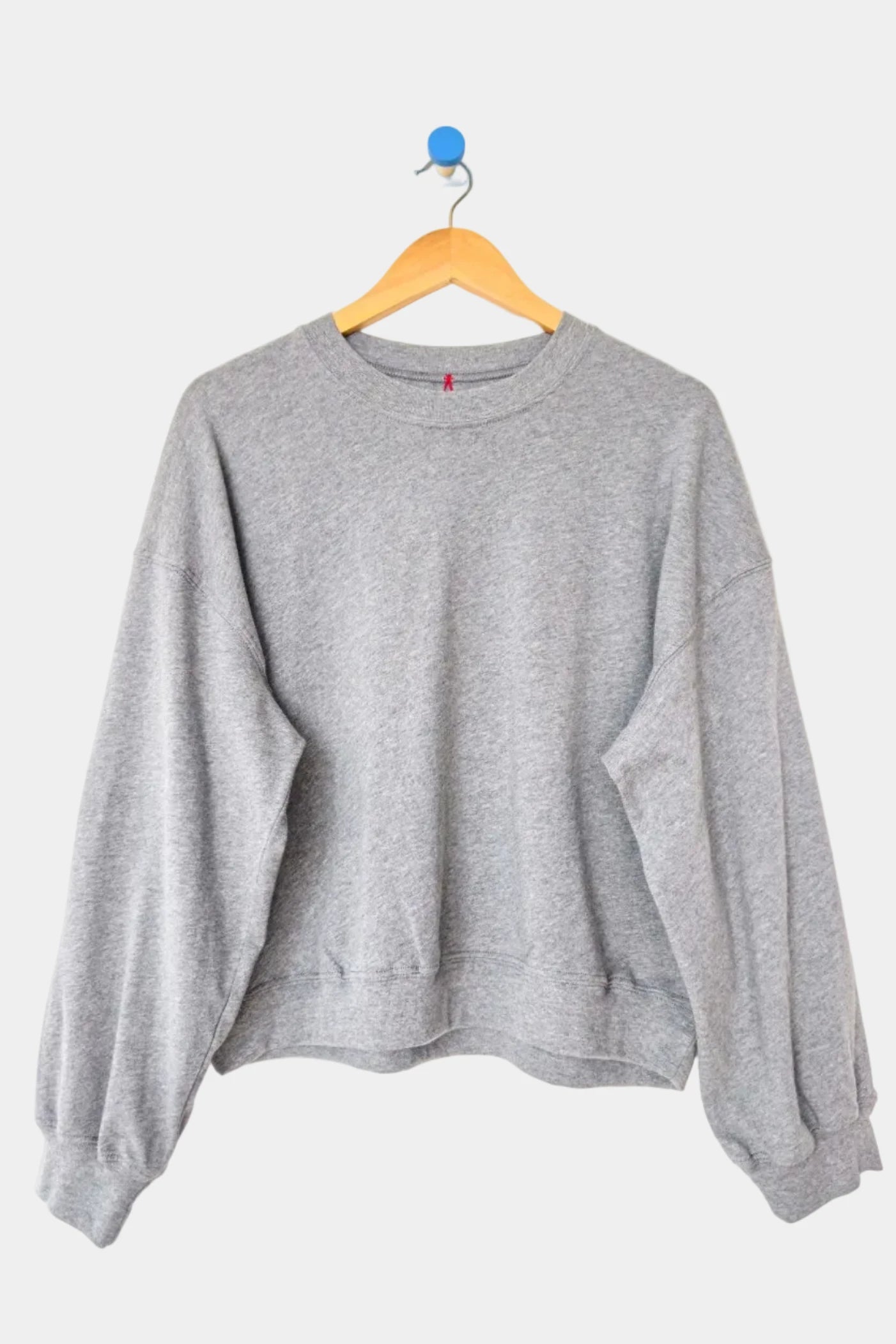 Gray sweatshirt on a wooden hanger against a white background