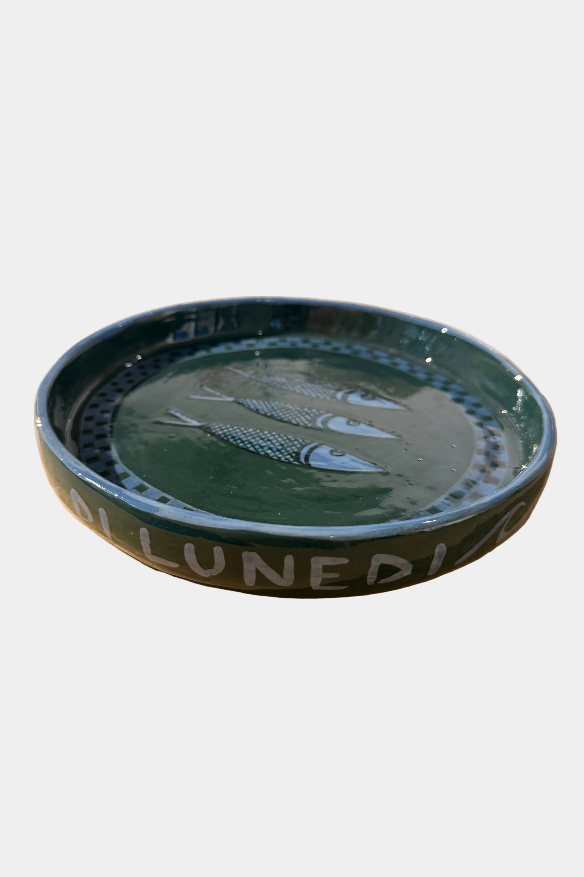 Green ceramic dish with fish design on a plain sureface
