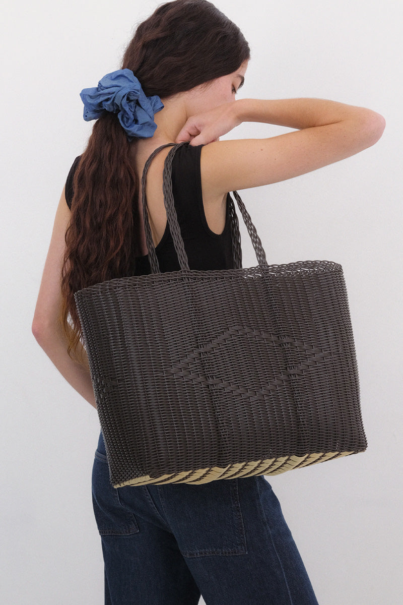 Woman holding a large woven bag against a white background