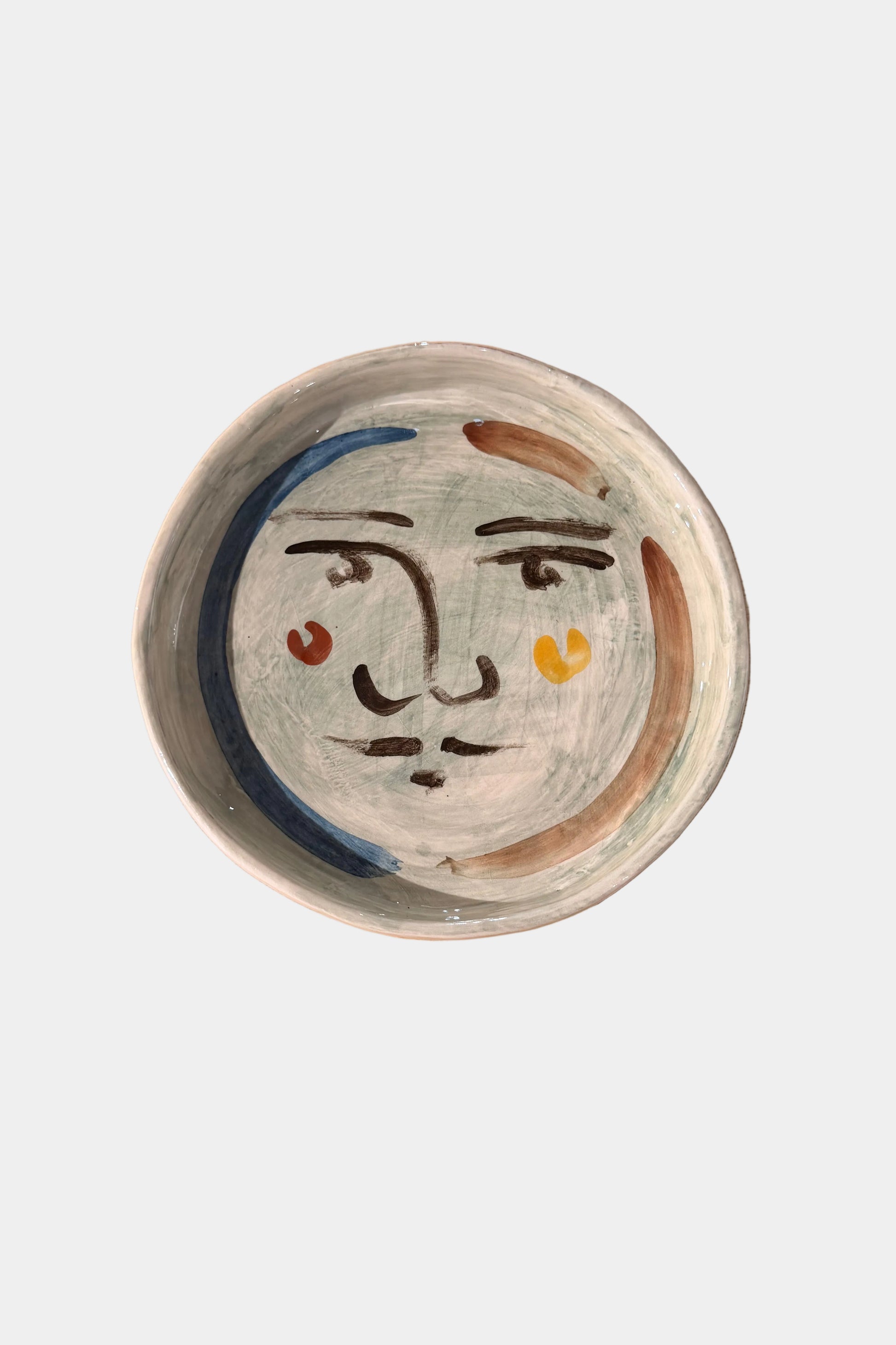 Ceramic plate with face design on a plain surface