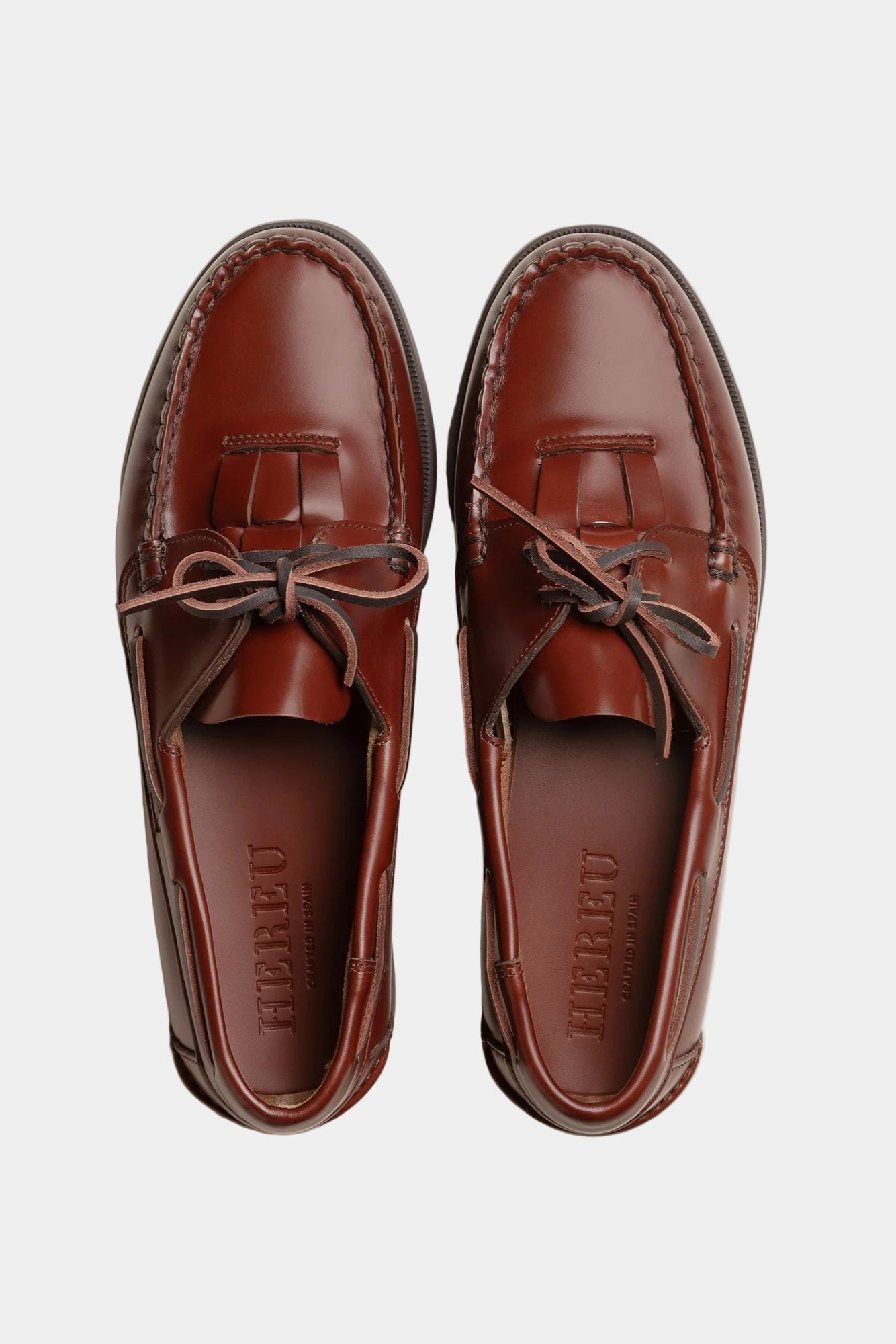 Pair of brown leather loafers with Hereu branding on a white background