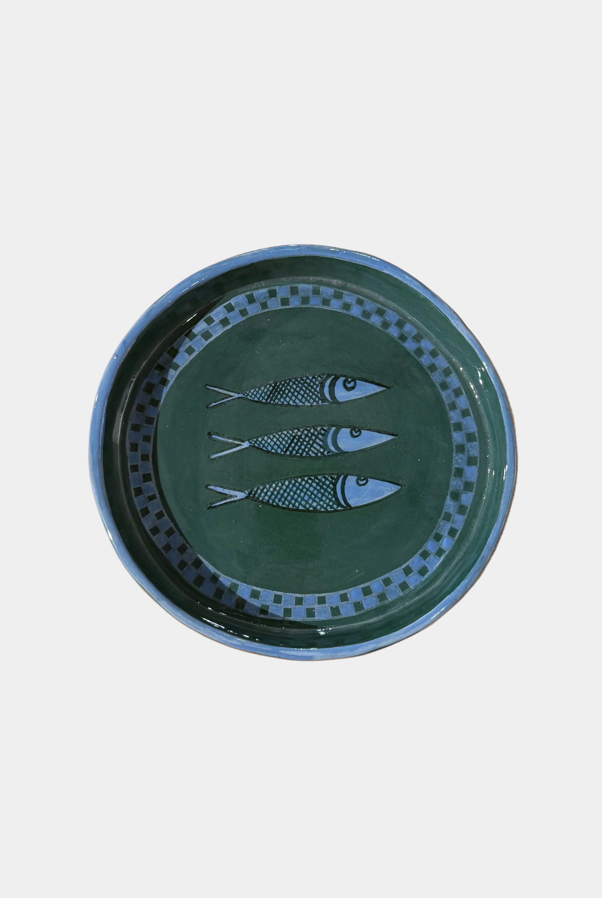 Green ceramic plate with fish design on a plain surface