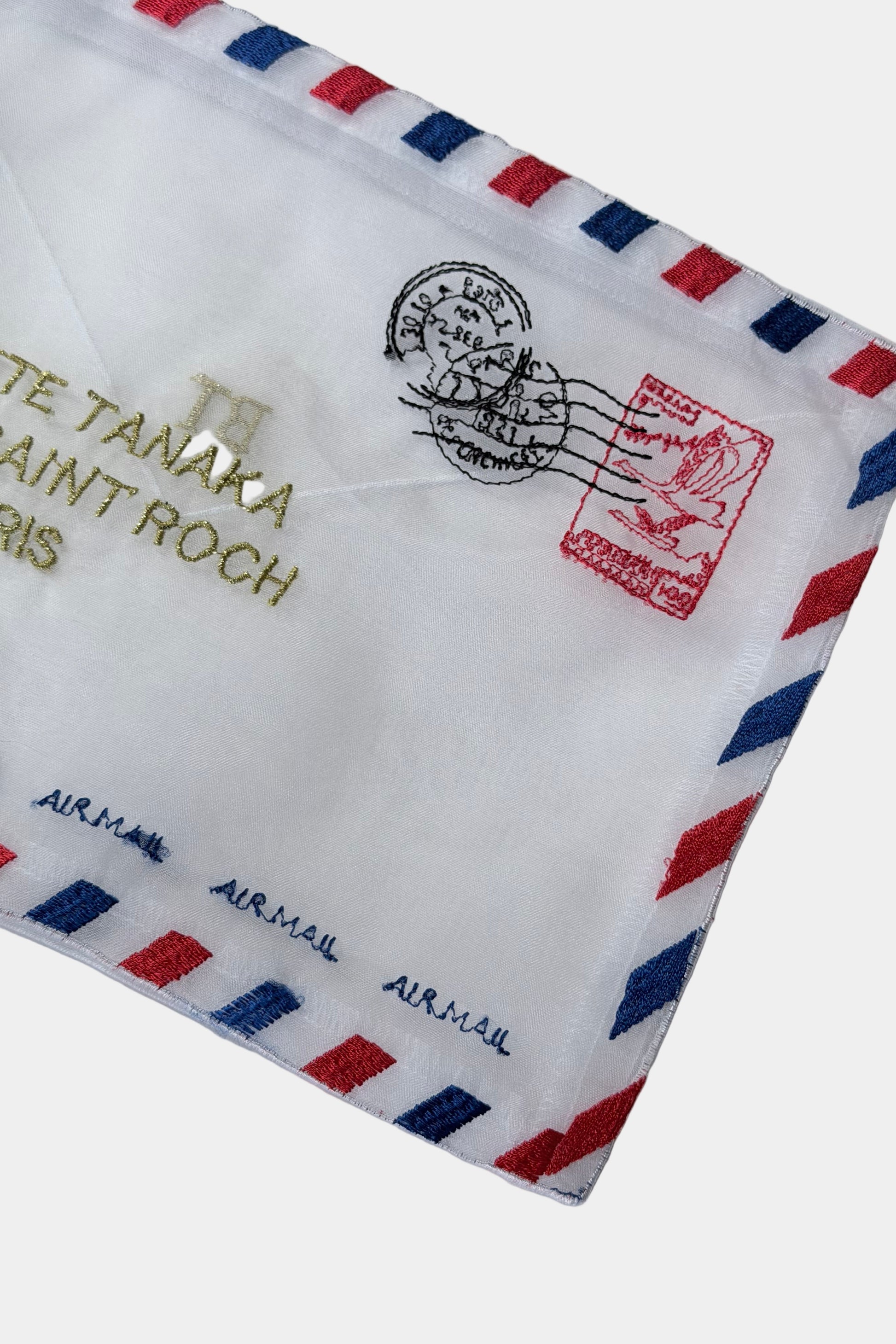 White organza pouch in the style of an envelope with embroidered airmail details on a white background