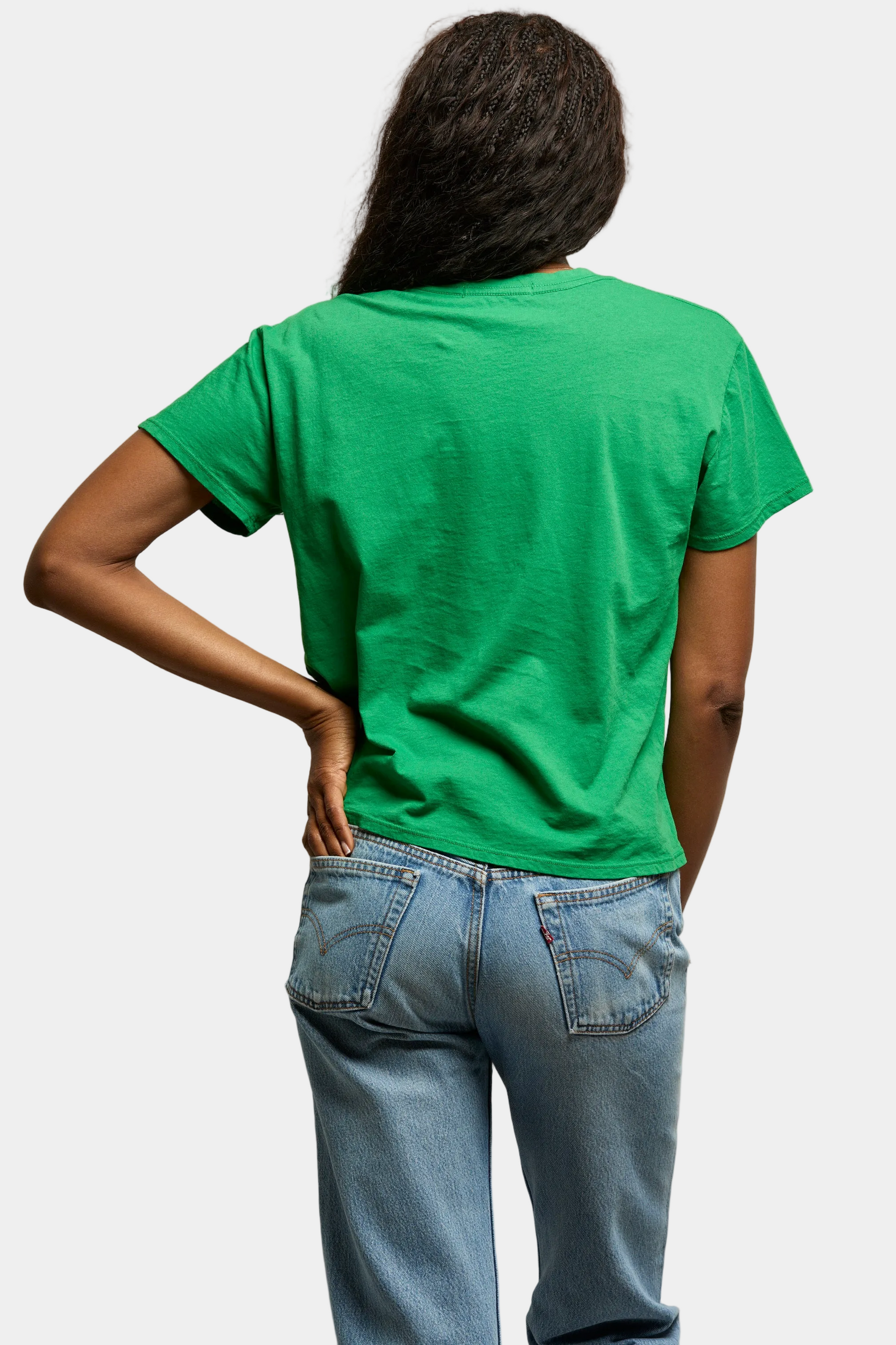 Person wearing a green t-shirt and blue jeans against a plain background
