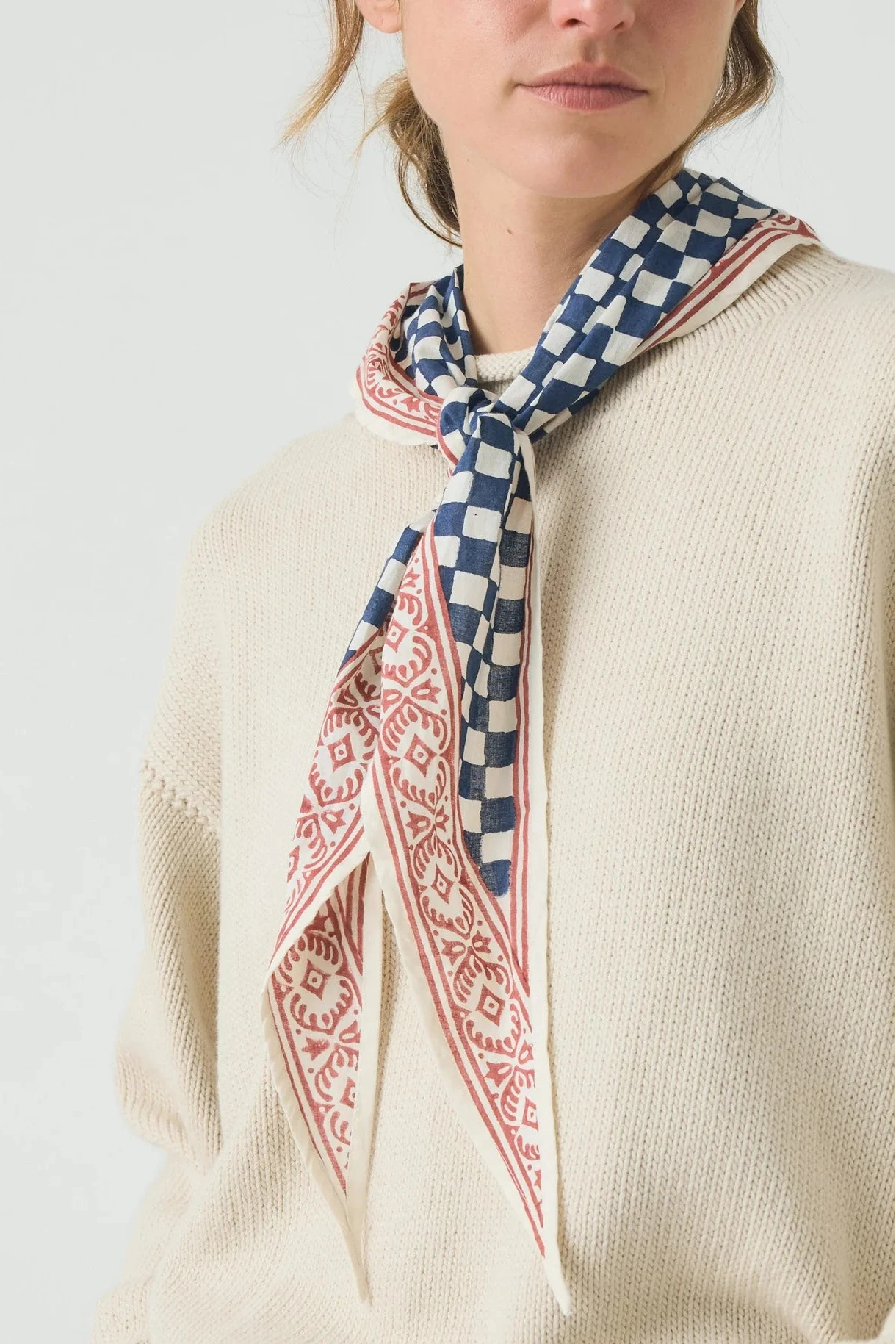 Person wearing a patterned scarf with a neutral background