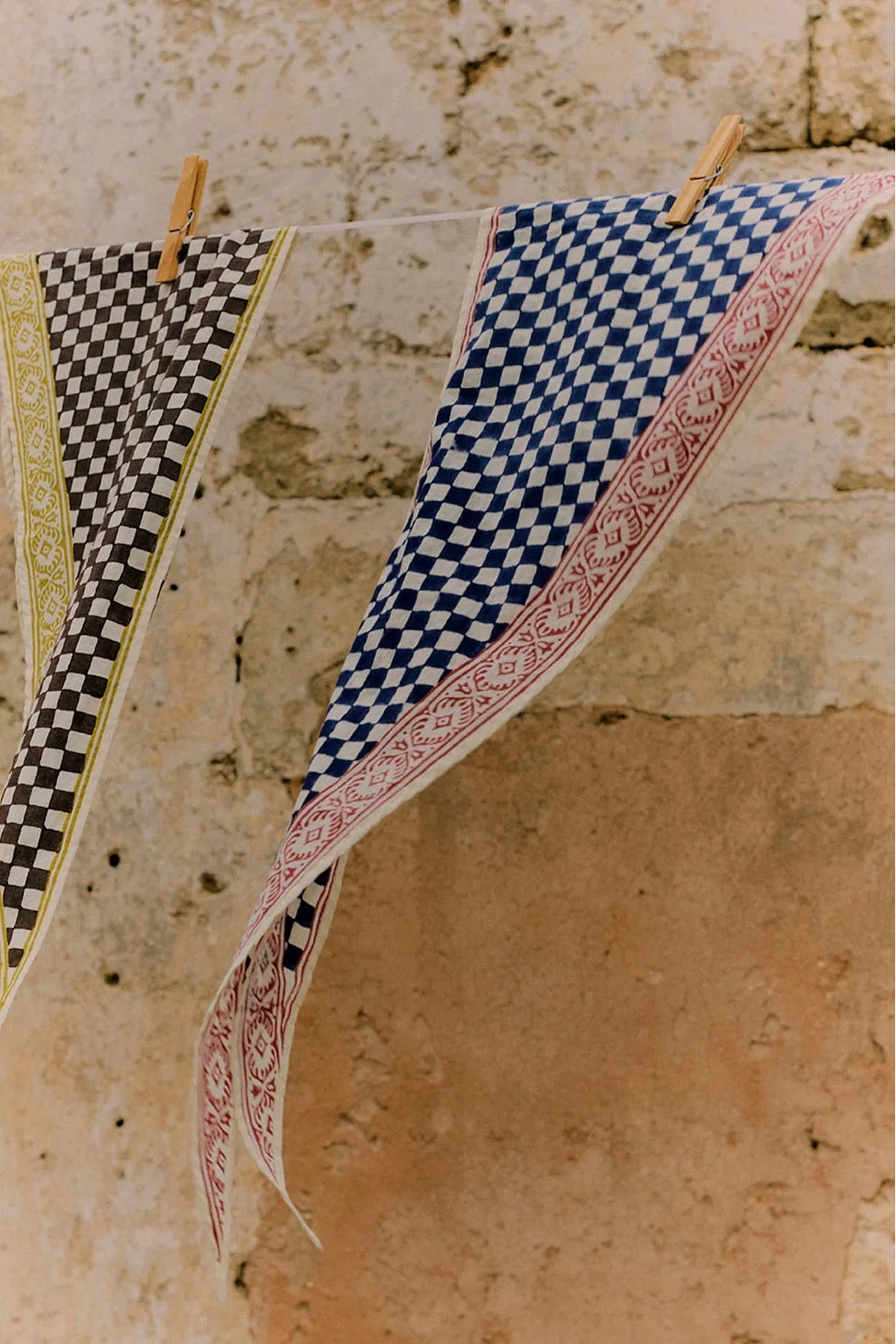 Blue and white checkered scarf with red border on a light gray background