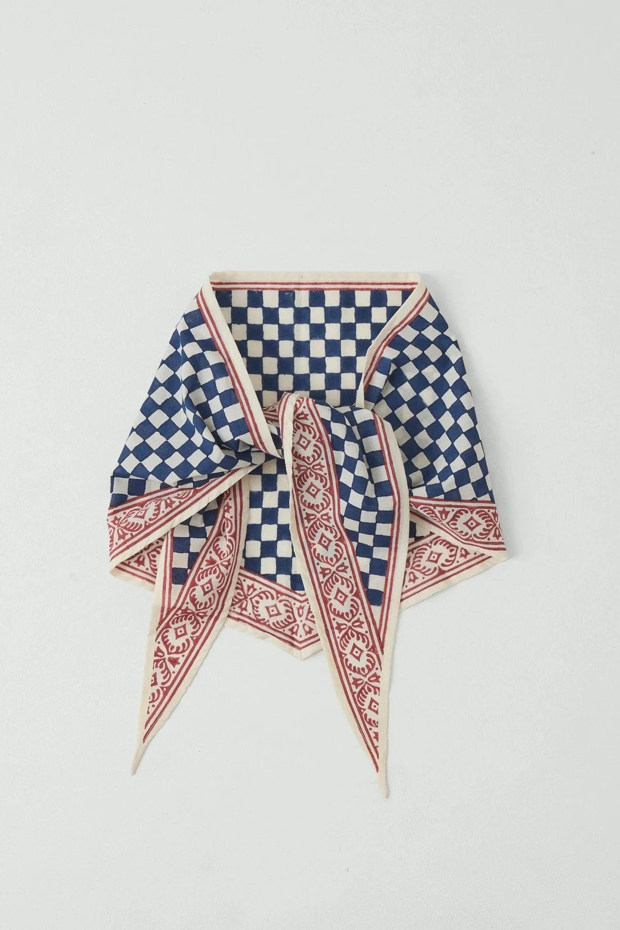 Blue and white checkered scarf with red border on a light gray background