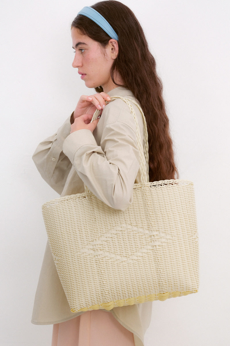 Woman holding a woven tote bag against a white background