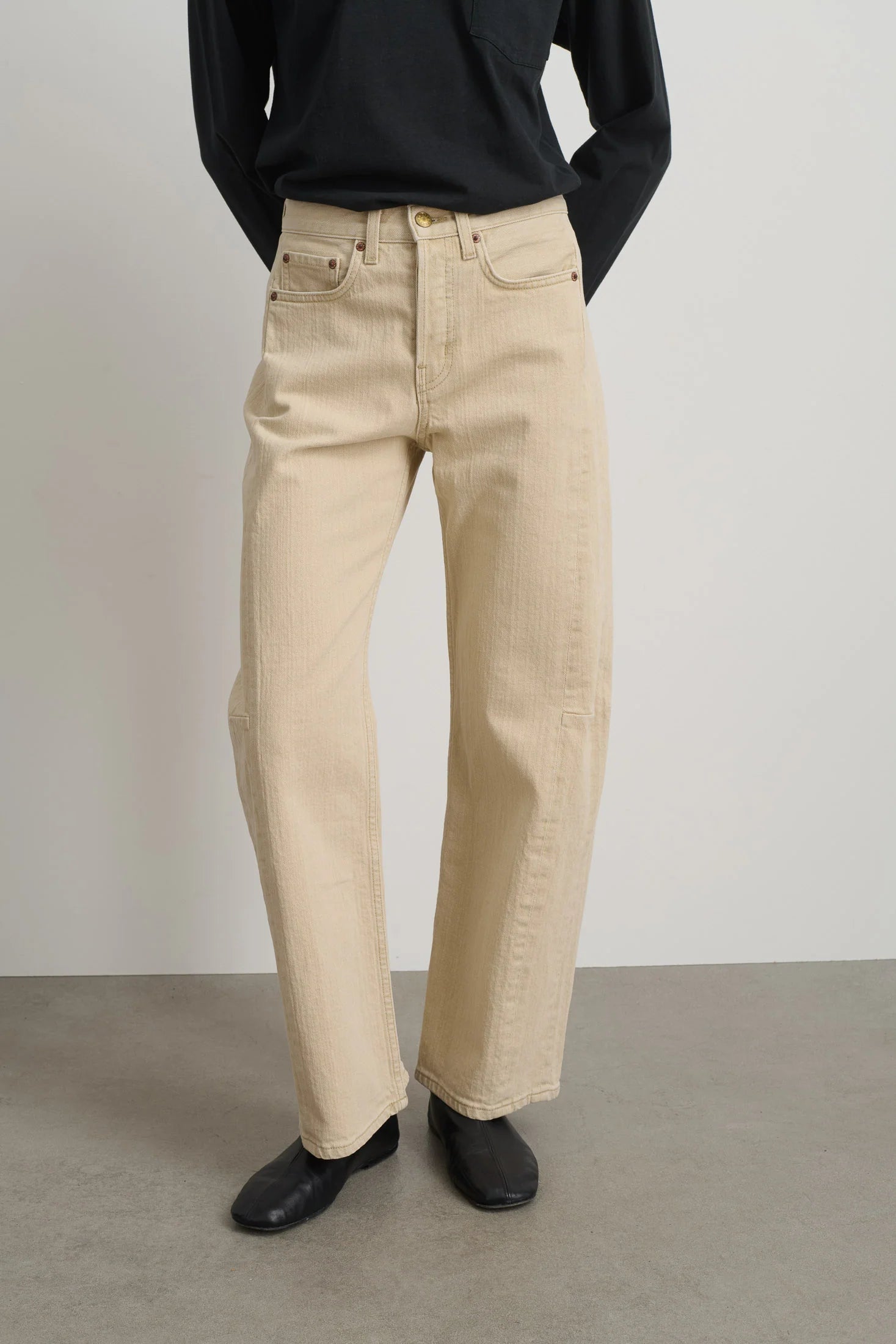 Person wearing beige pants and black shoes on a plain background