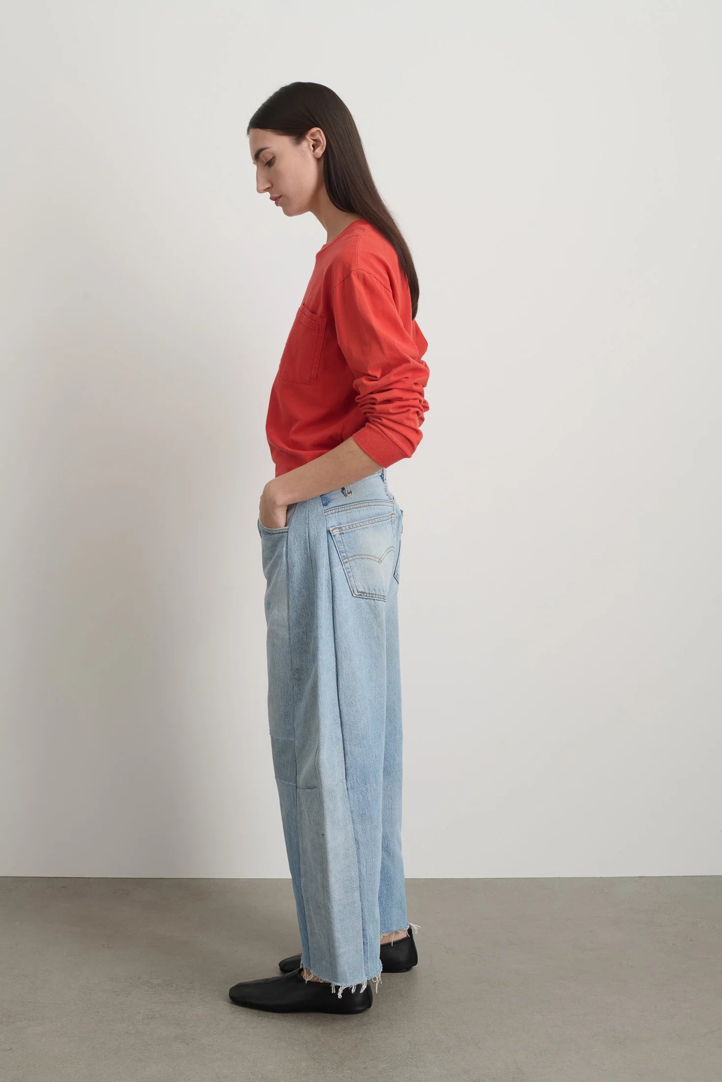 Person wearing a red sweater and light blue jeans against a plain background