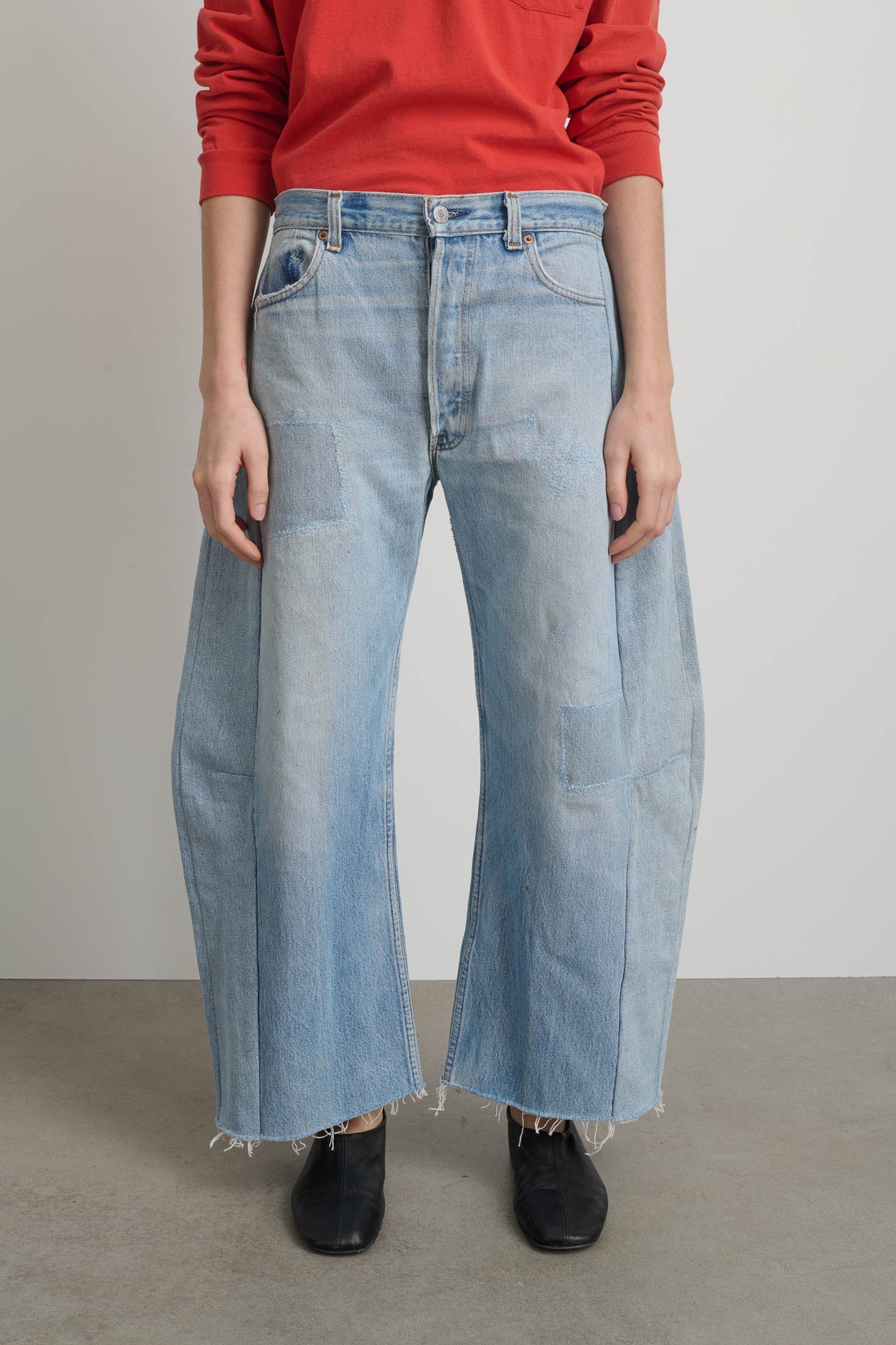 Person wearing light blue jeans and a red top on a plain background