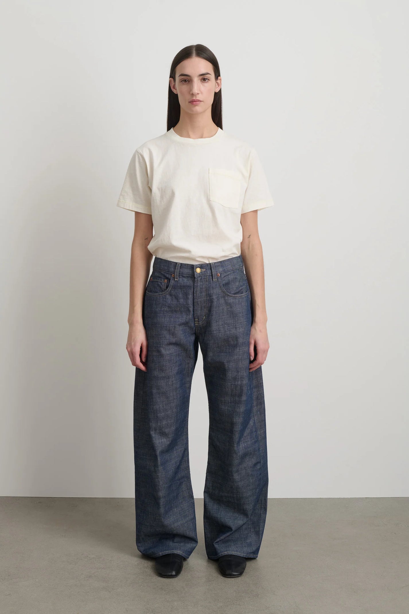 Person wearing a white t-shirt and blue jeans against a plain background