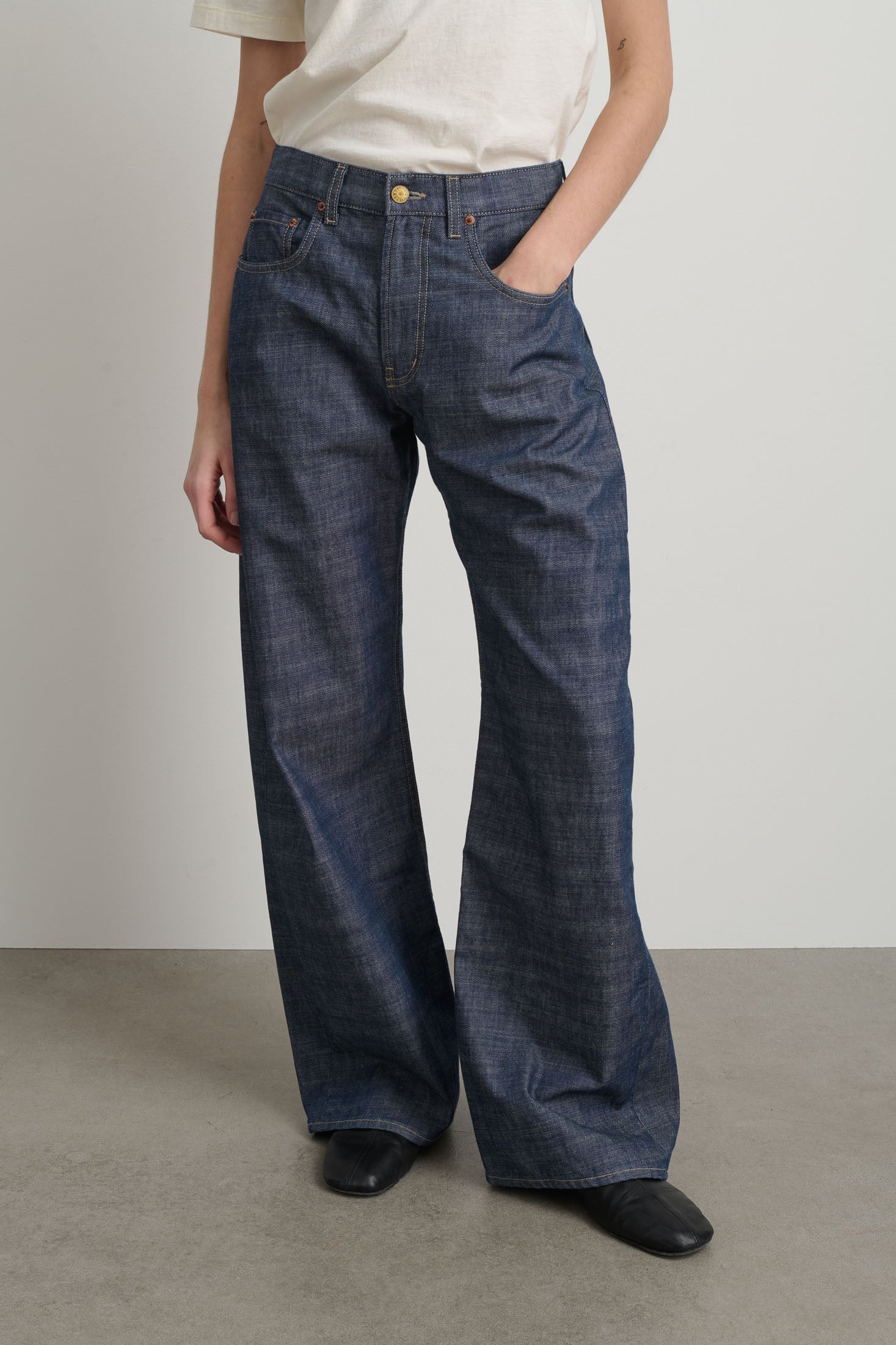 Person wearing blue flared jeans on a plain background