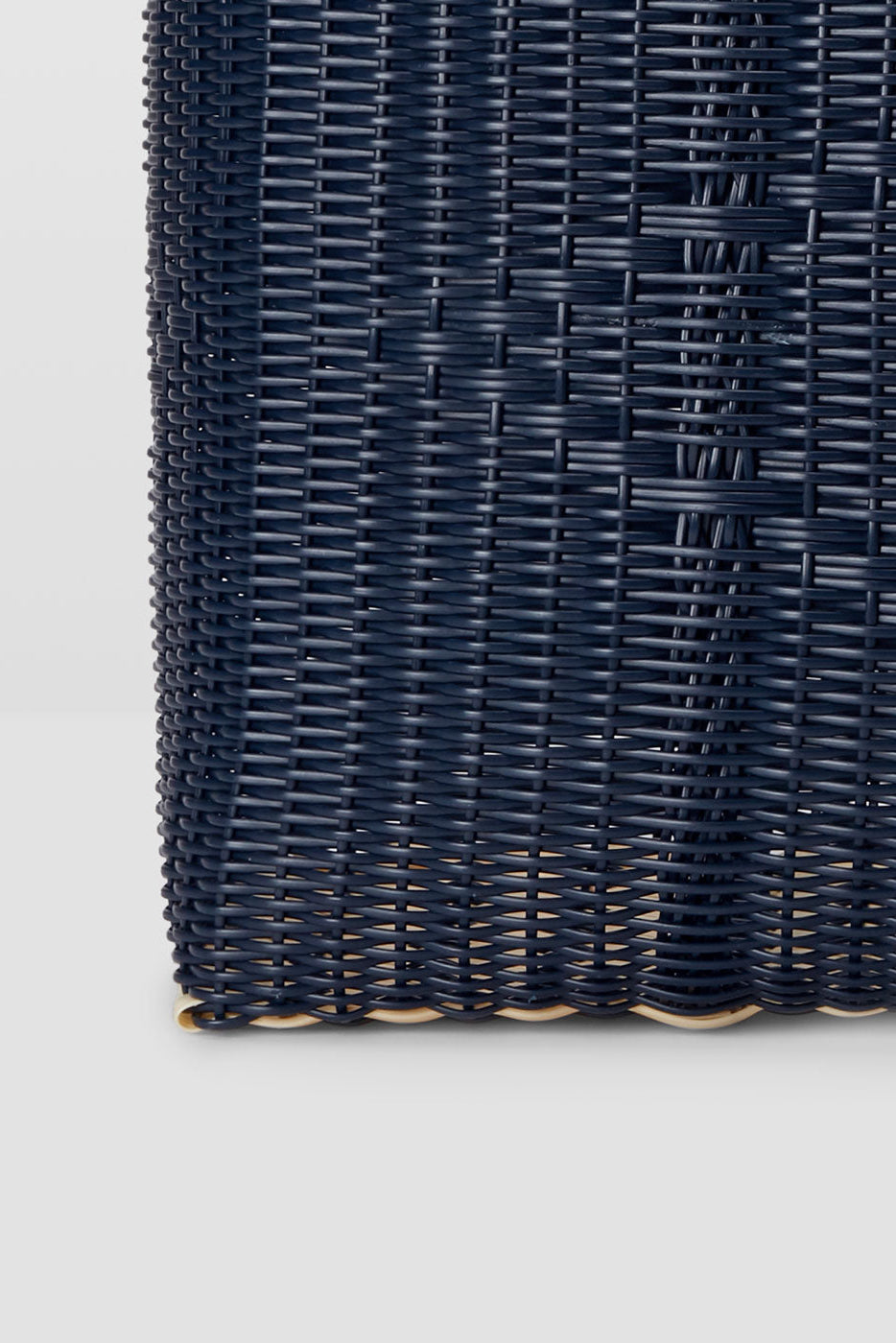 Close-up of a dark blue woven bag on a light gray background