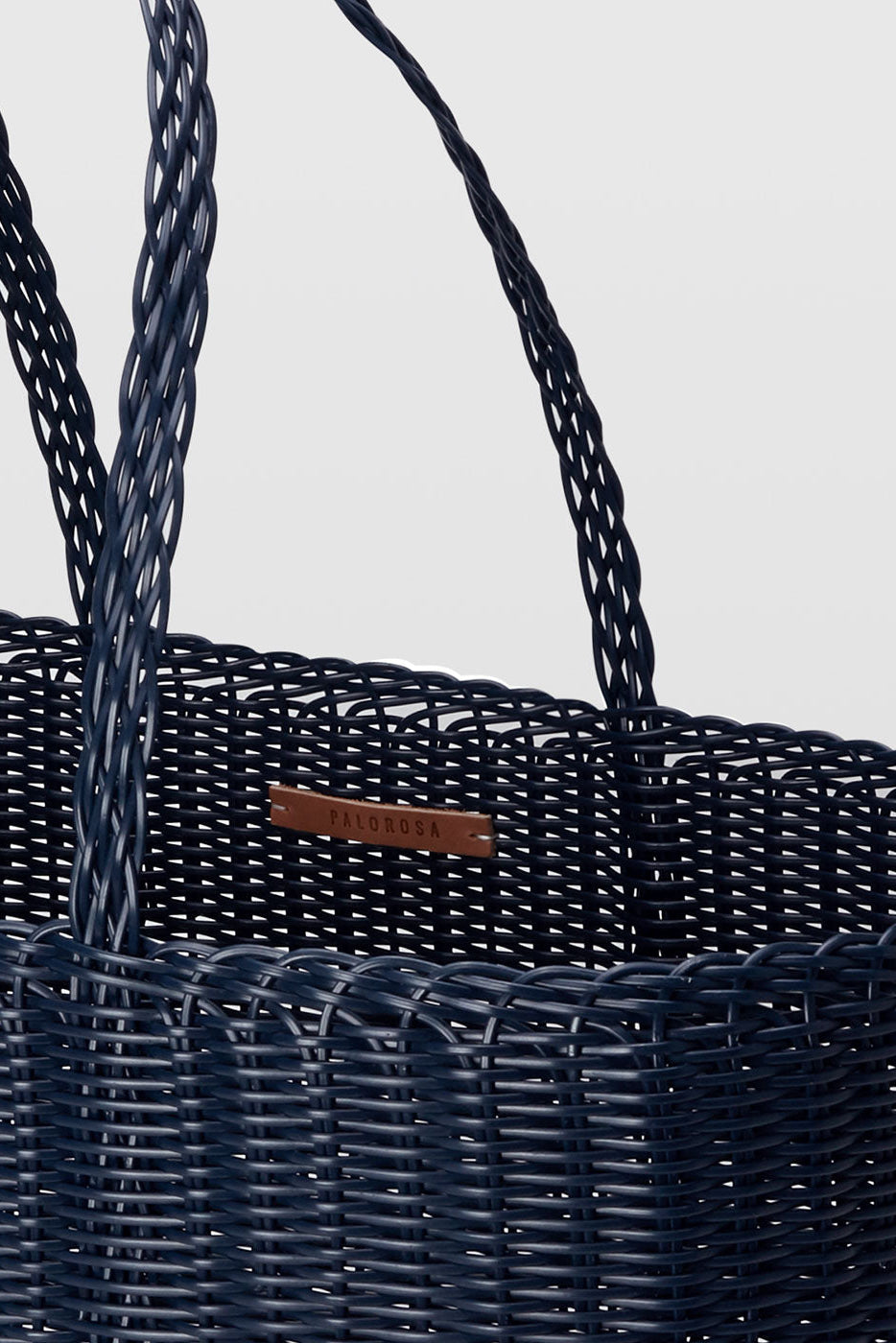 Navy blue woven basket with a handle on a light gray background