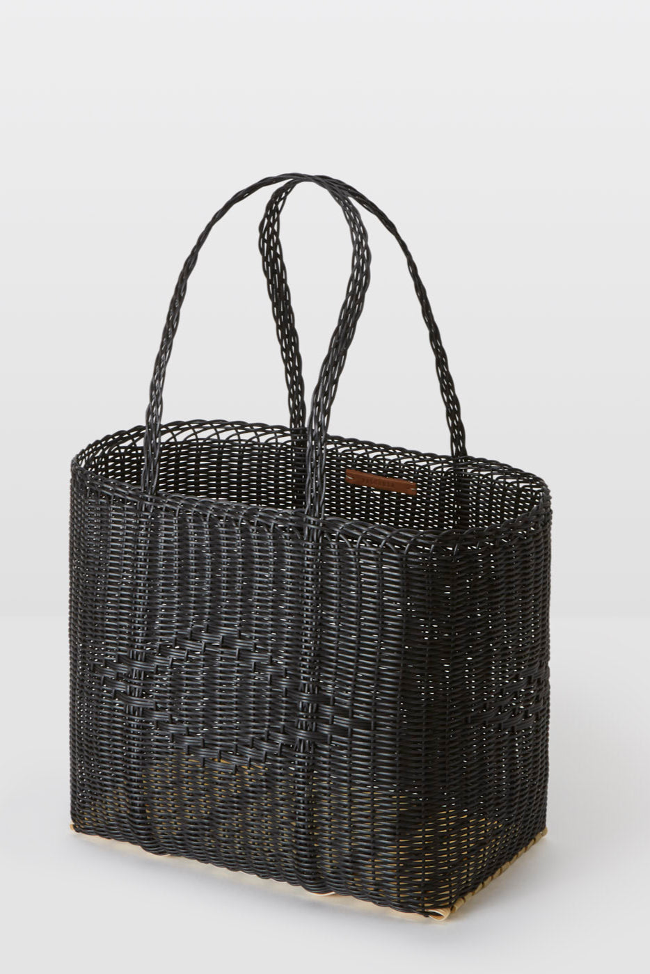 Black woven basket with handles on a white background