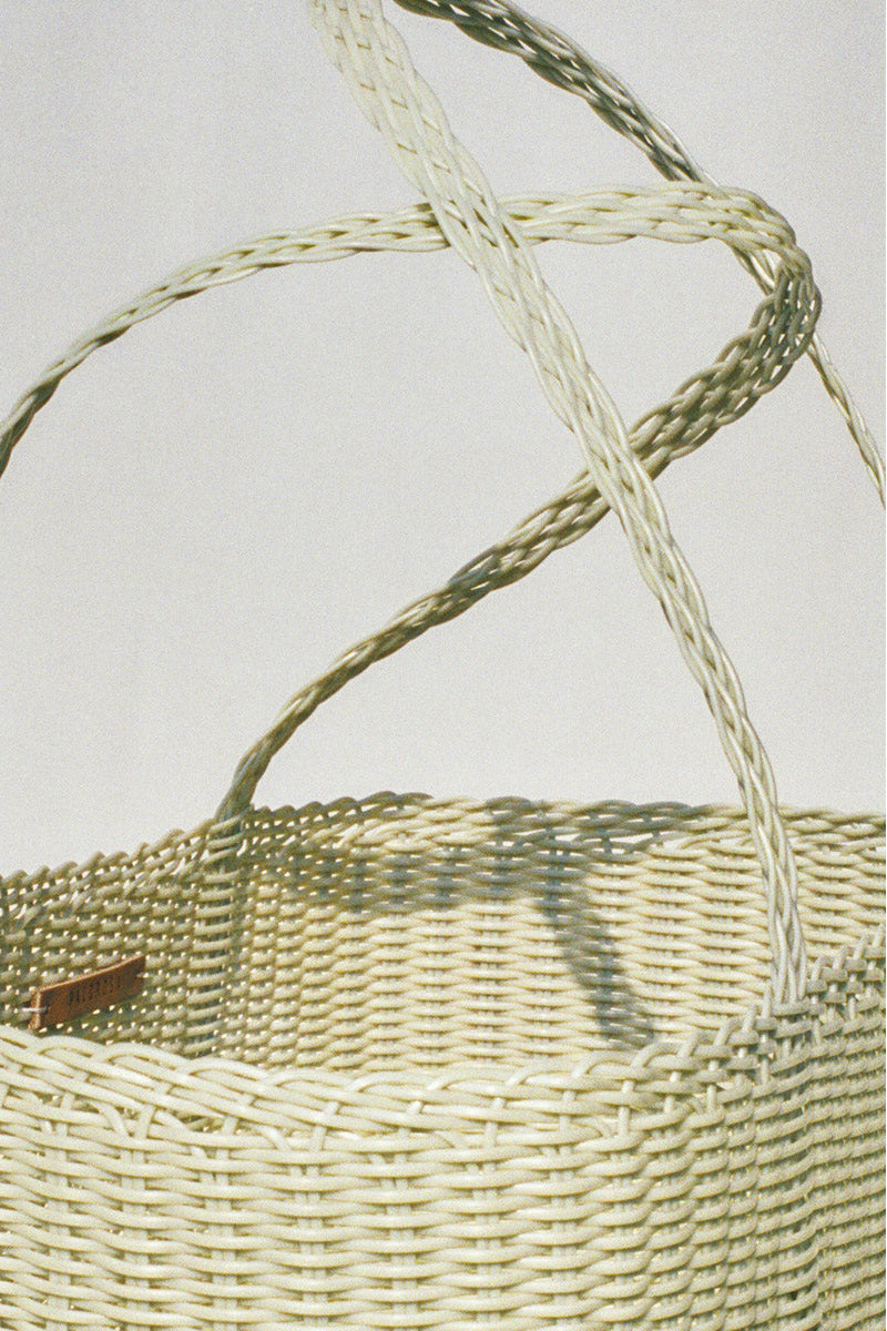 Woven basket with a handle on a light gray background