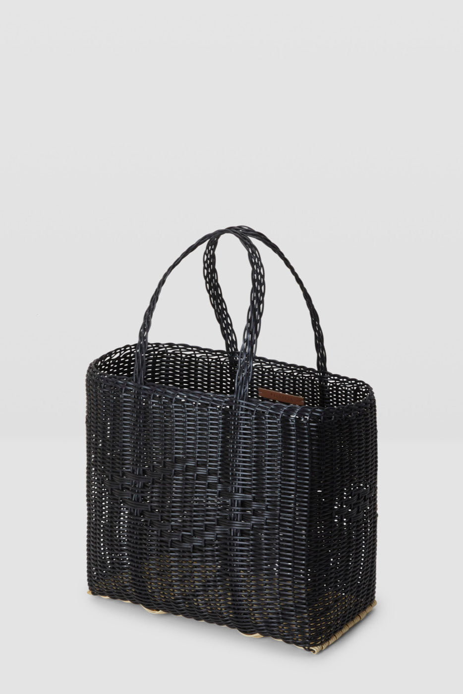 Black woven handbag with handles on a light gray background
