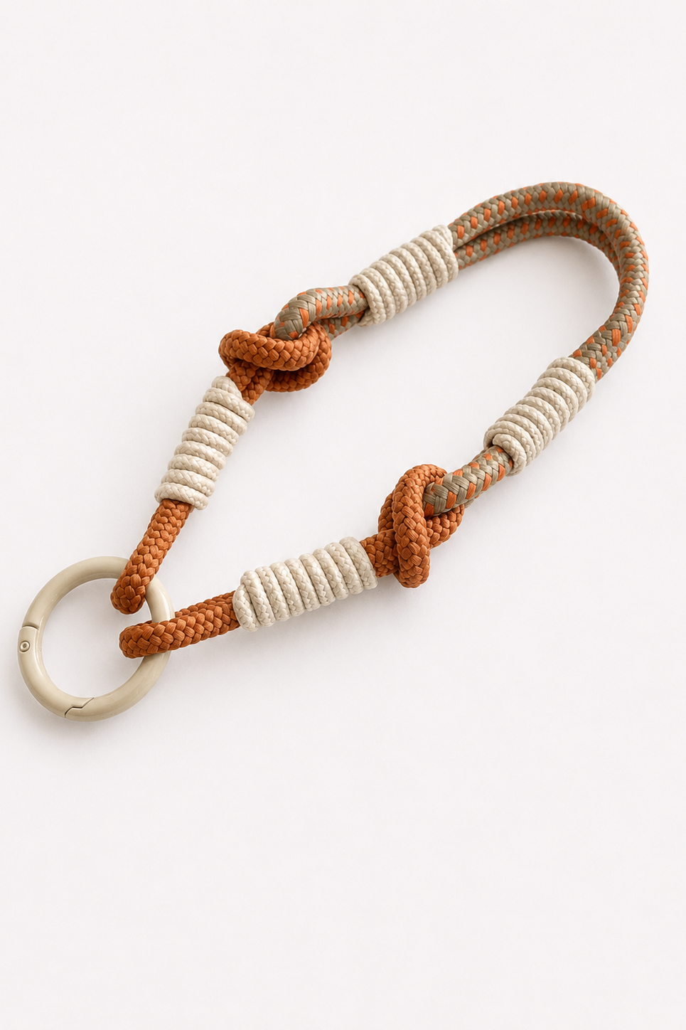 A braided rope keychain or phone wrist strap with a cream-colored metal key ring, featuring textured white wrapped sections and two orange-brown knots on a light gray background - East Coast General