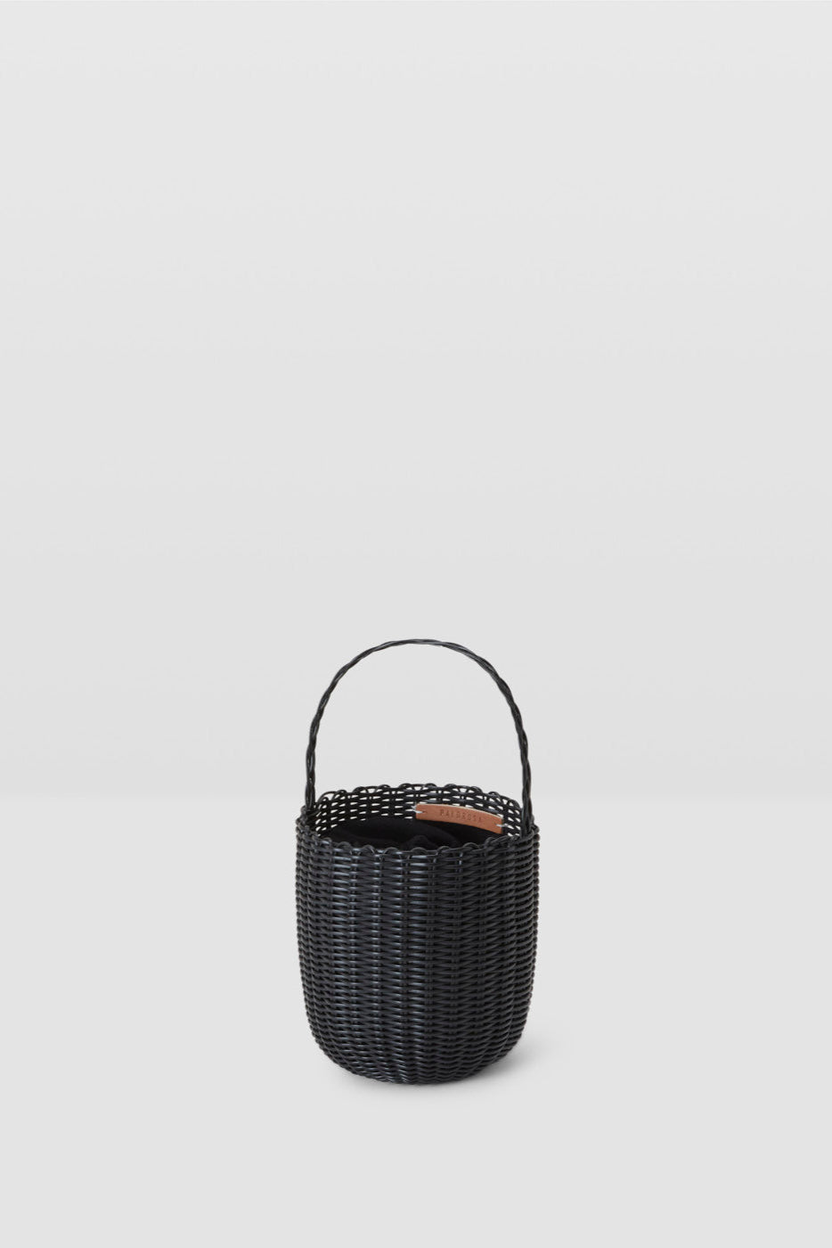 Black woven basket with handle on a light gray background