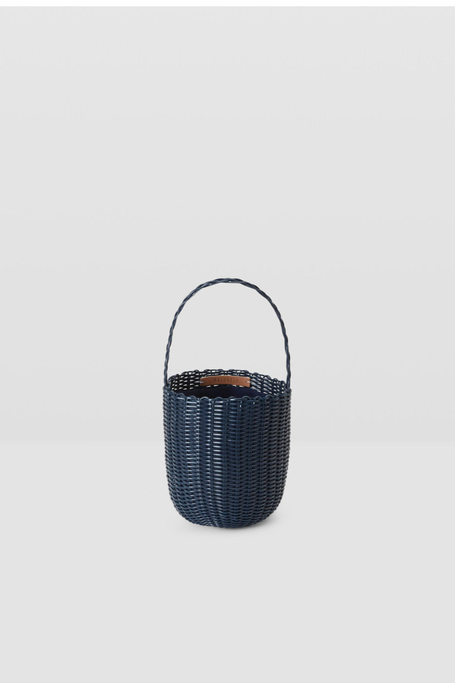 Black woven basket with handle on a light gray background