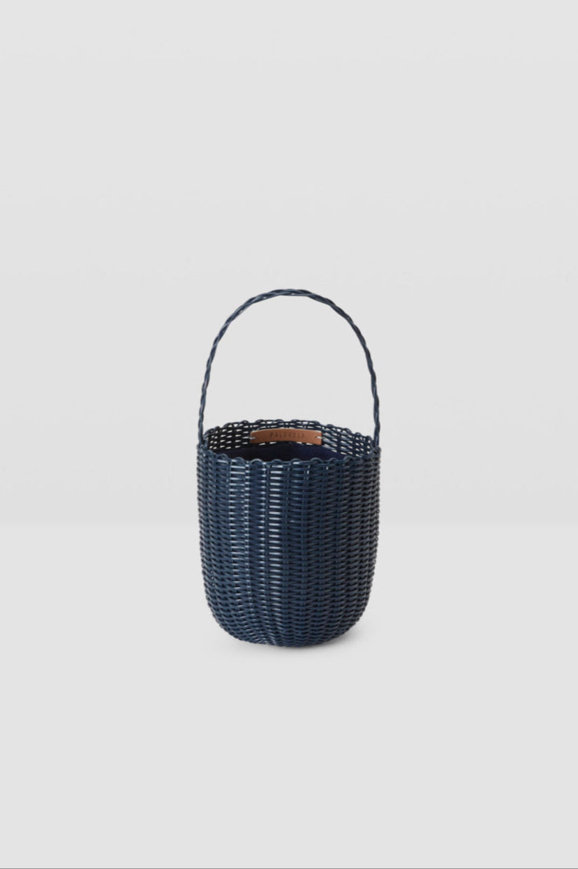 Black woven basket with handle on a light gray background