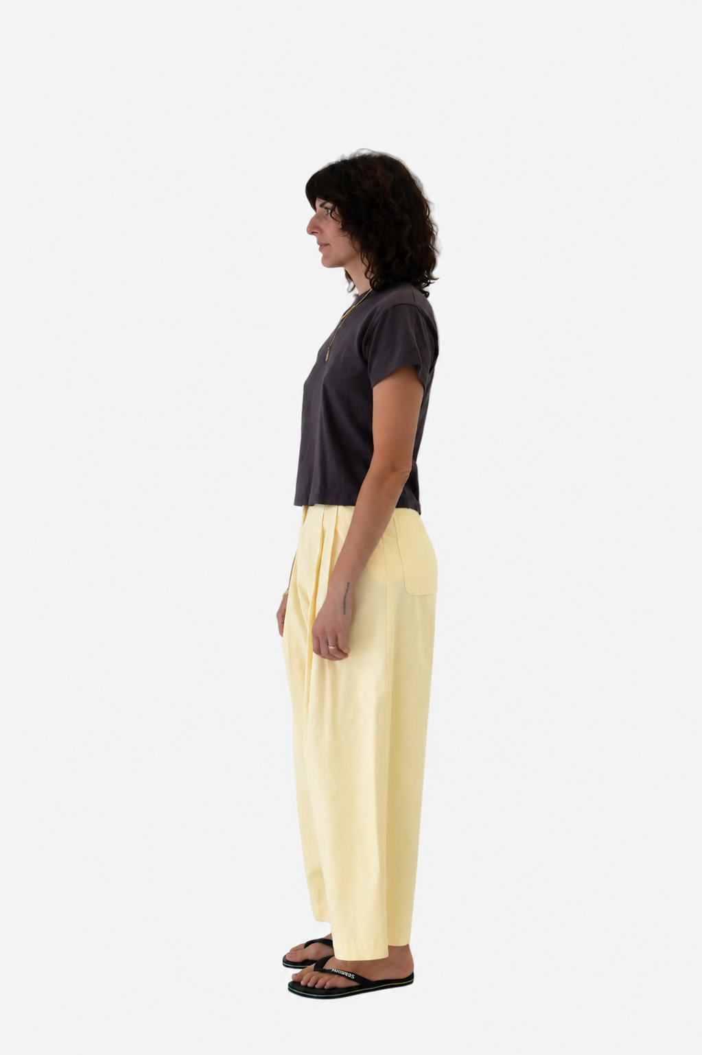 A  women wearing No. 53 pants in butter with Sunray hiaka tshirt in raisin, viewed from the side - East Coast General 