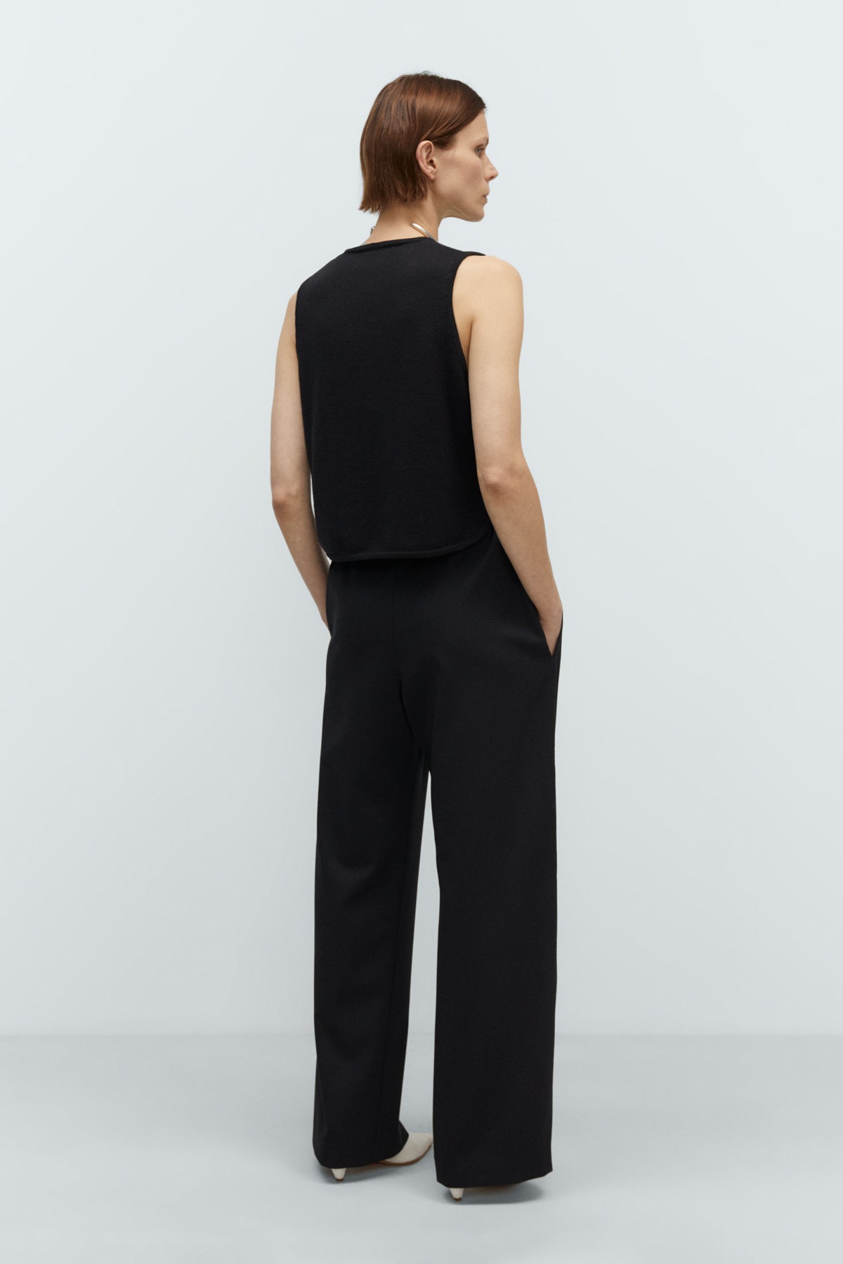 Person wearing a black sleeveless top and pants on a white background