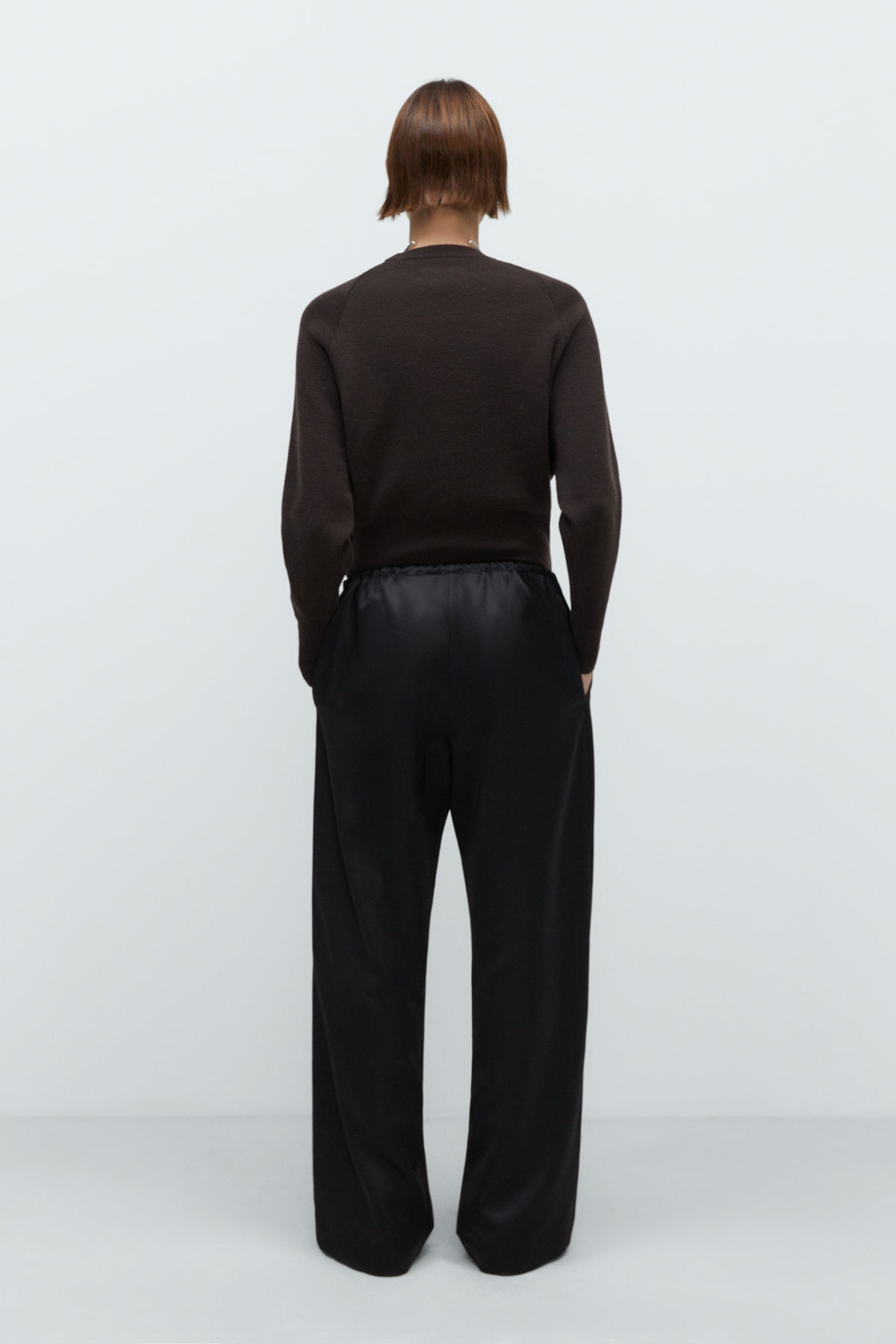 Person wearing a black sweater and pants on a white background