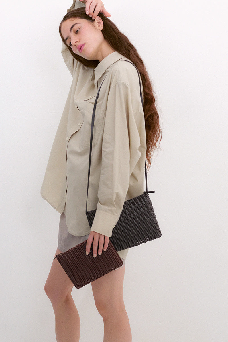Woman holding a woven handbag against a white background