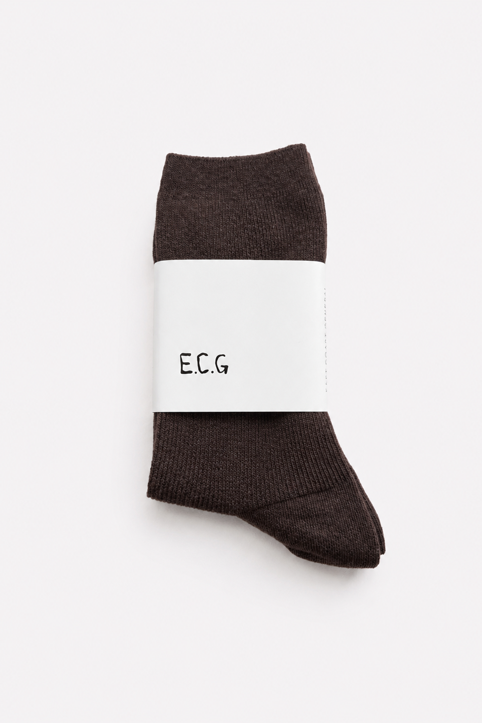 A pair of coffee brown coloured cotton ribbed crew socks wrapped in a white paper band with the brand name 'E.C.G’ - East Coast General 