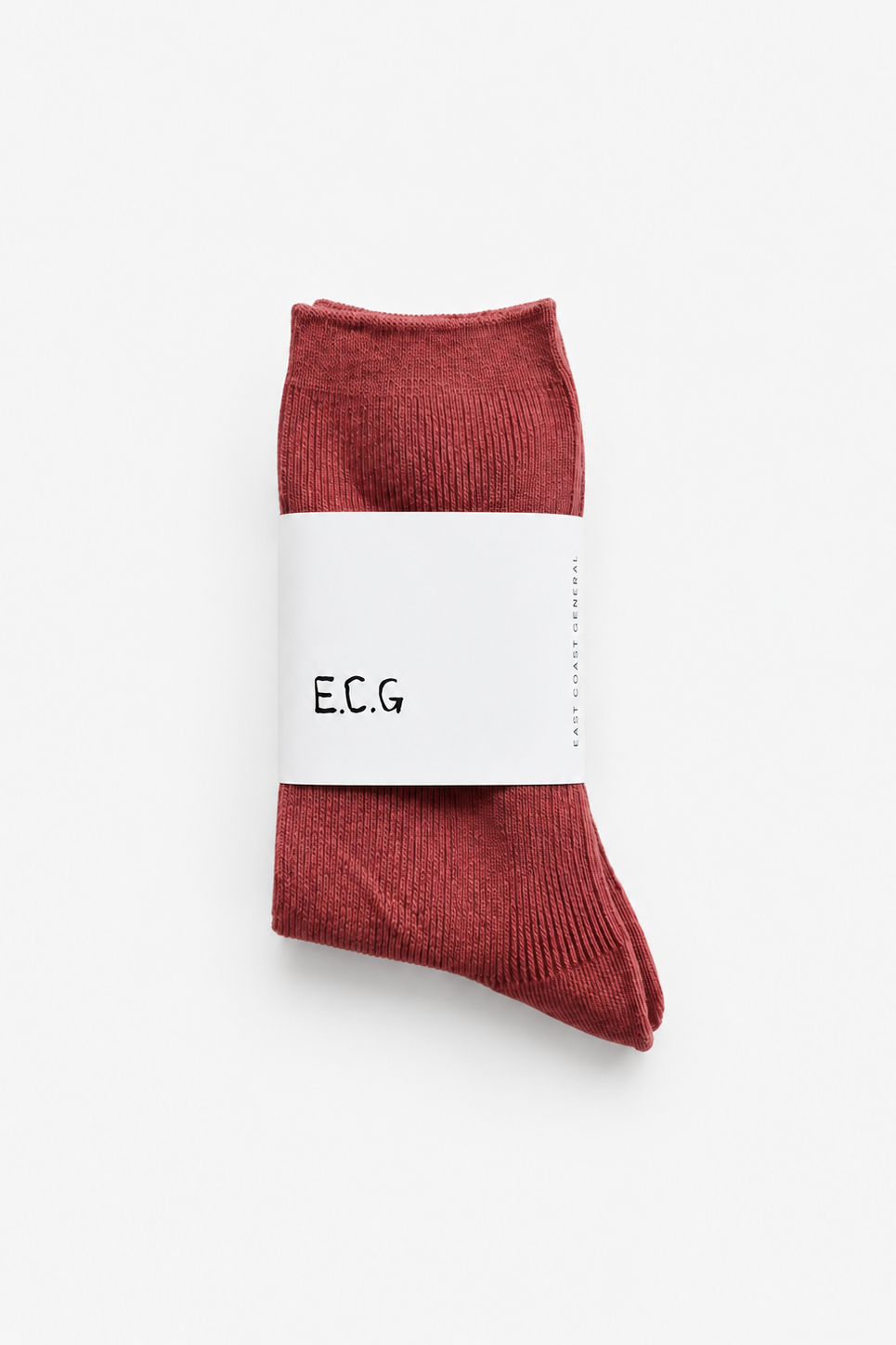 A pair of ribbed cotton crew socks in a muted brick red color, wrapped in a white paper band with the brand name 'E.C.G - East Coast General