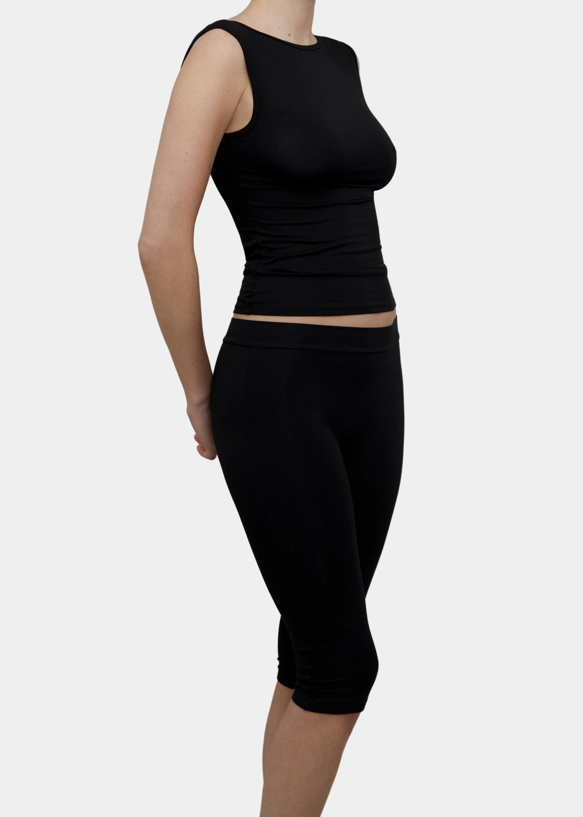 A model wearing Kye Intimates Recline Bateau sleeveless top and matching black capri leggings viewed from the side - East Coast General