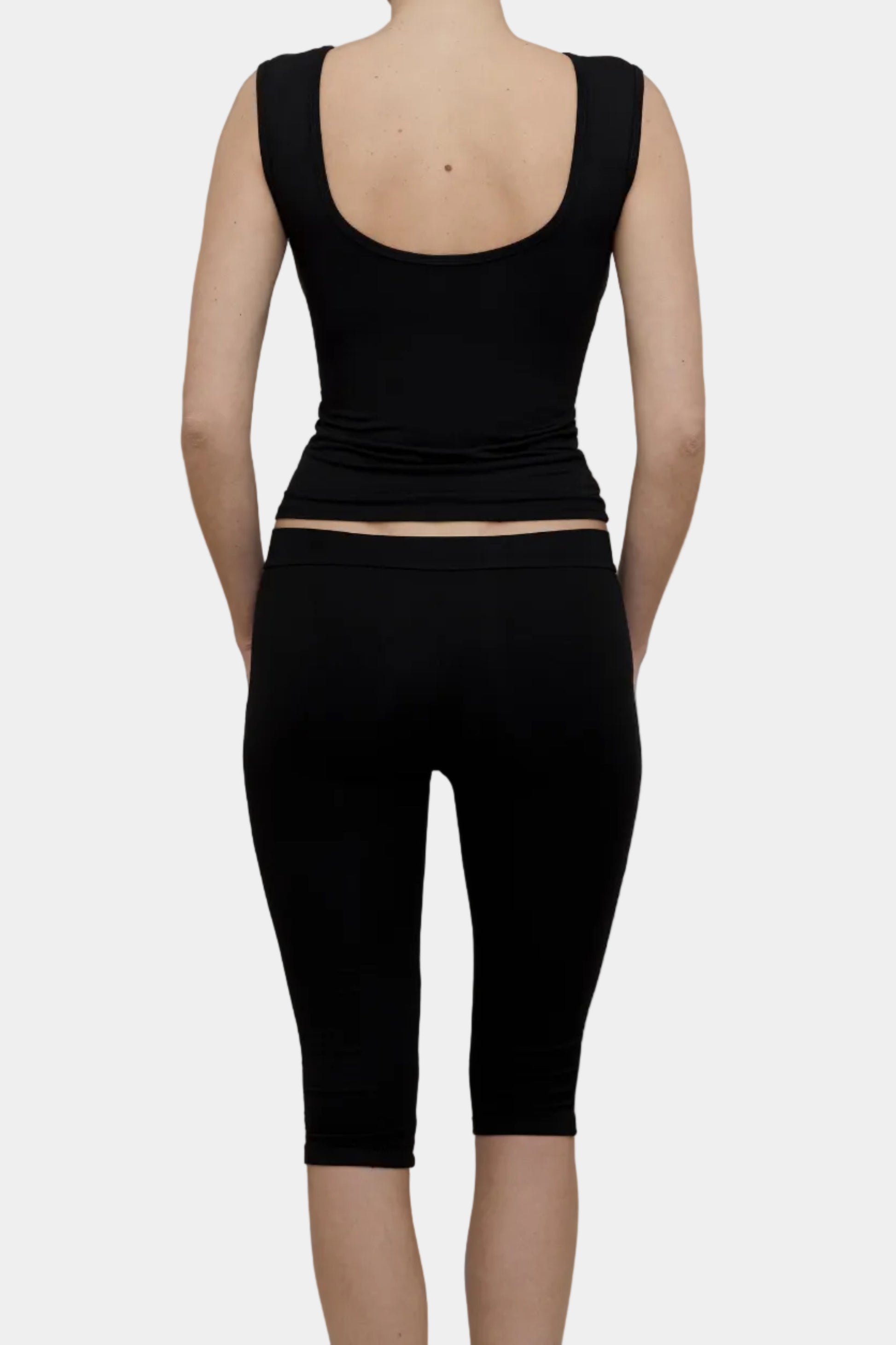 A model wearing Kye Intimates Recline Bateau sleeveless top and matching black capri leggings viewed from the back - East Coast General