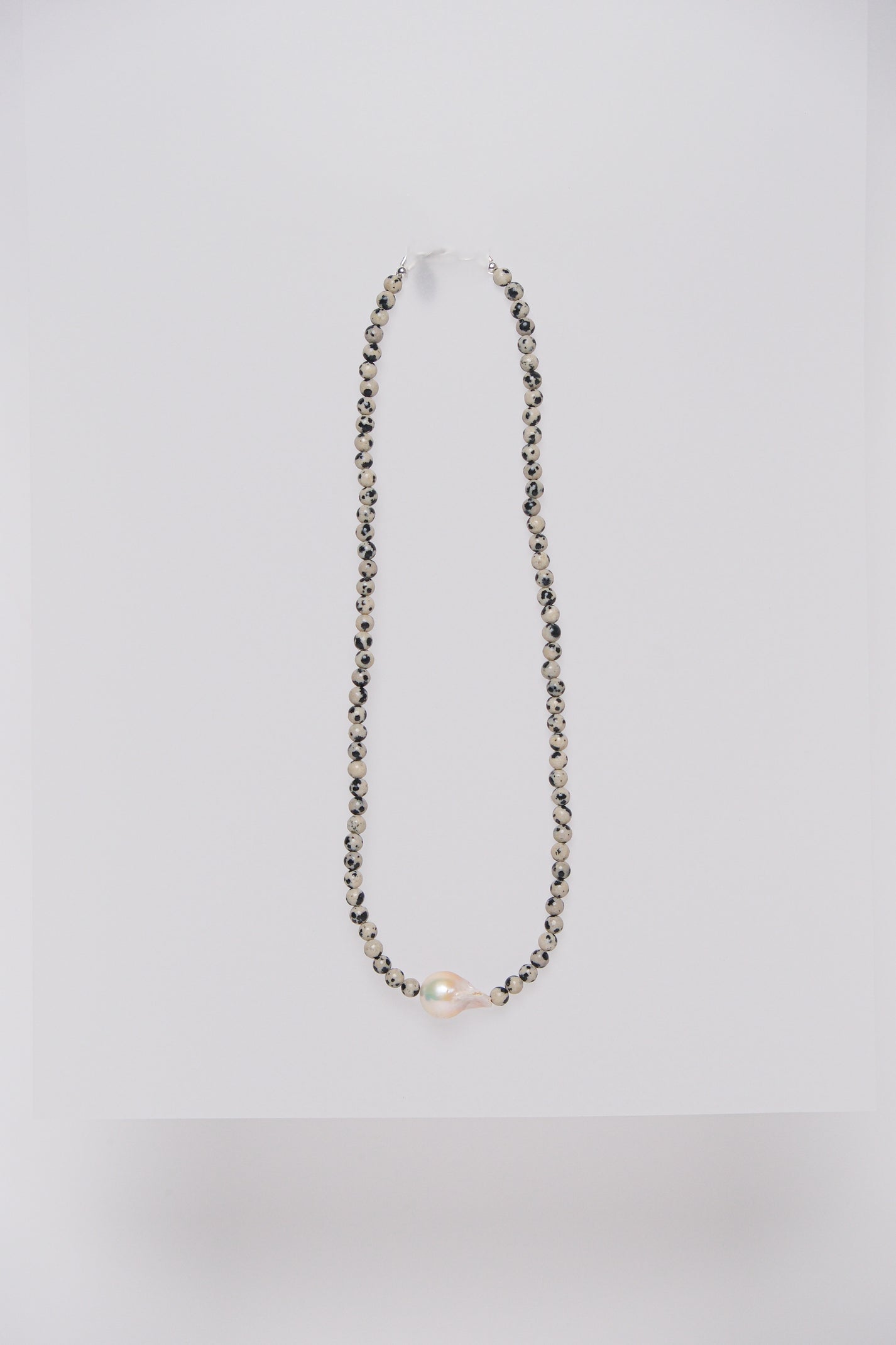 A necklace with Dalmatian Jasper semi-precious stones and a single baroque fresh water pearl.