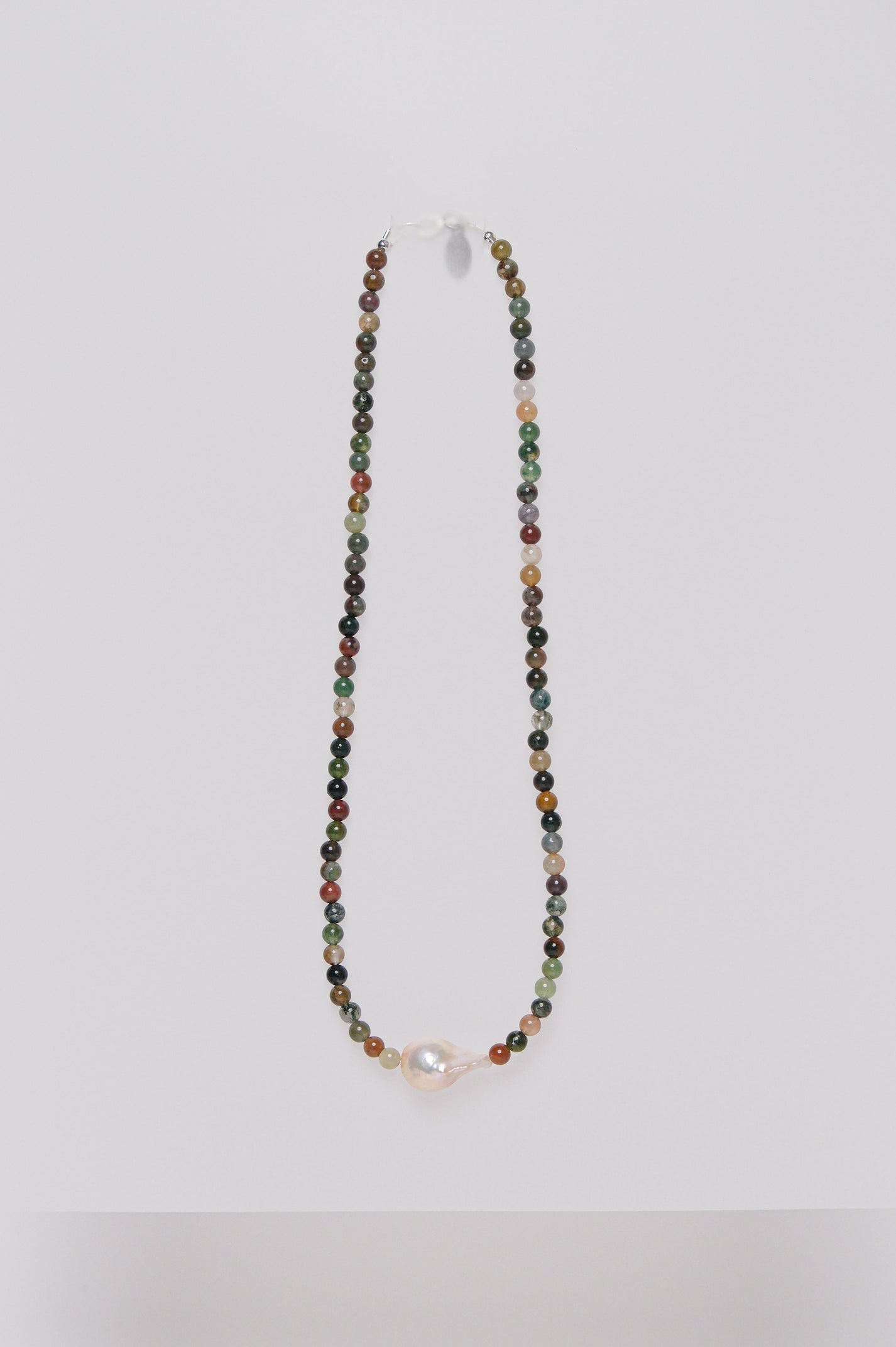 A beaded necklace with multicolored semi-precious stones and a single baroque fresh water pearl, displayed against a white background.
