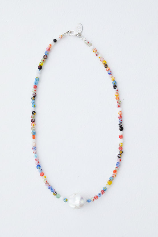 Necklace with multicolored beads and a pearl on a light gray background