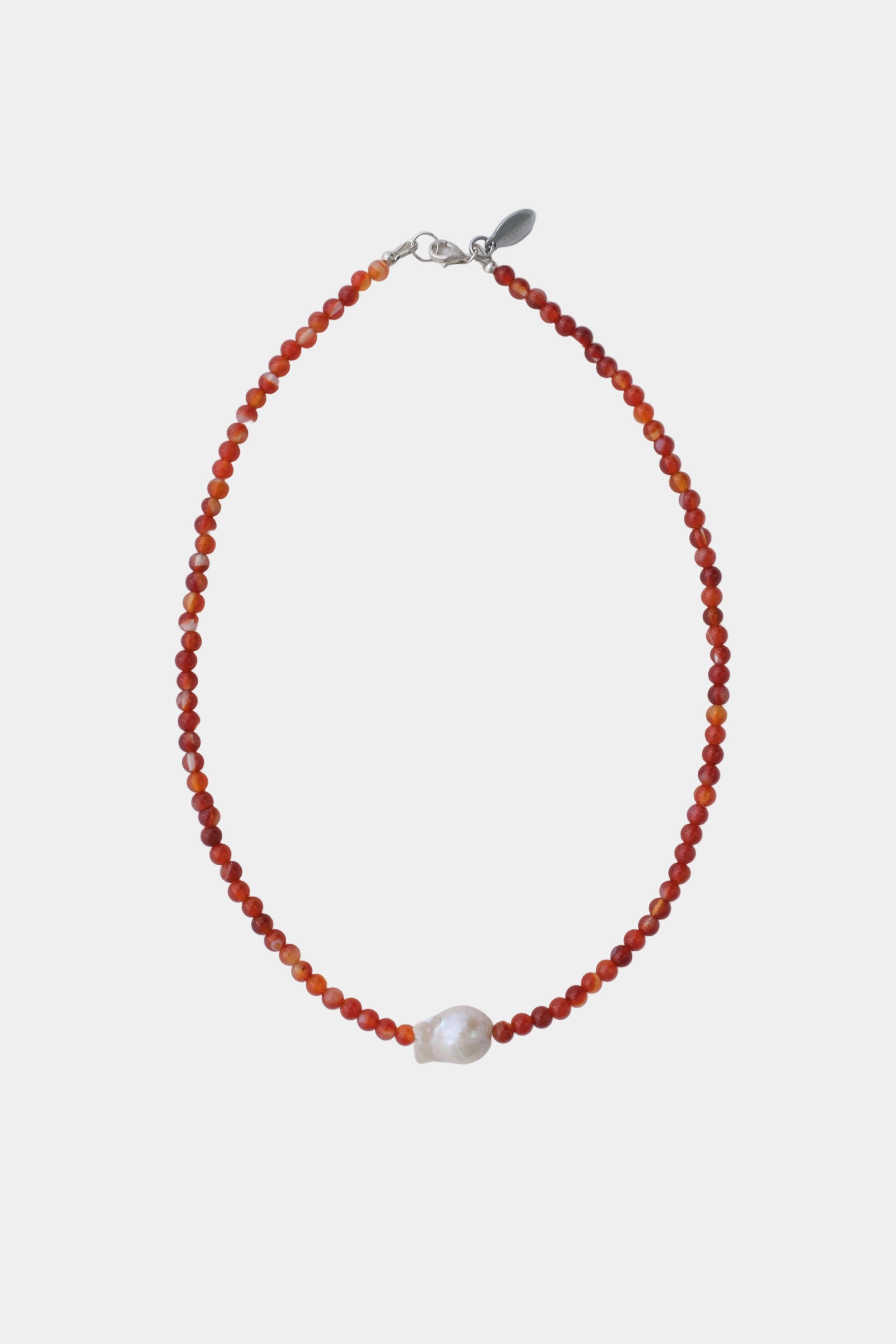 Necklace with orange beads and a pearl on a light gray background